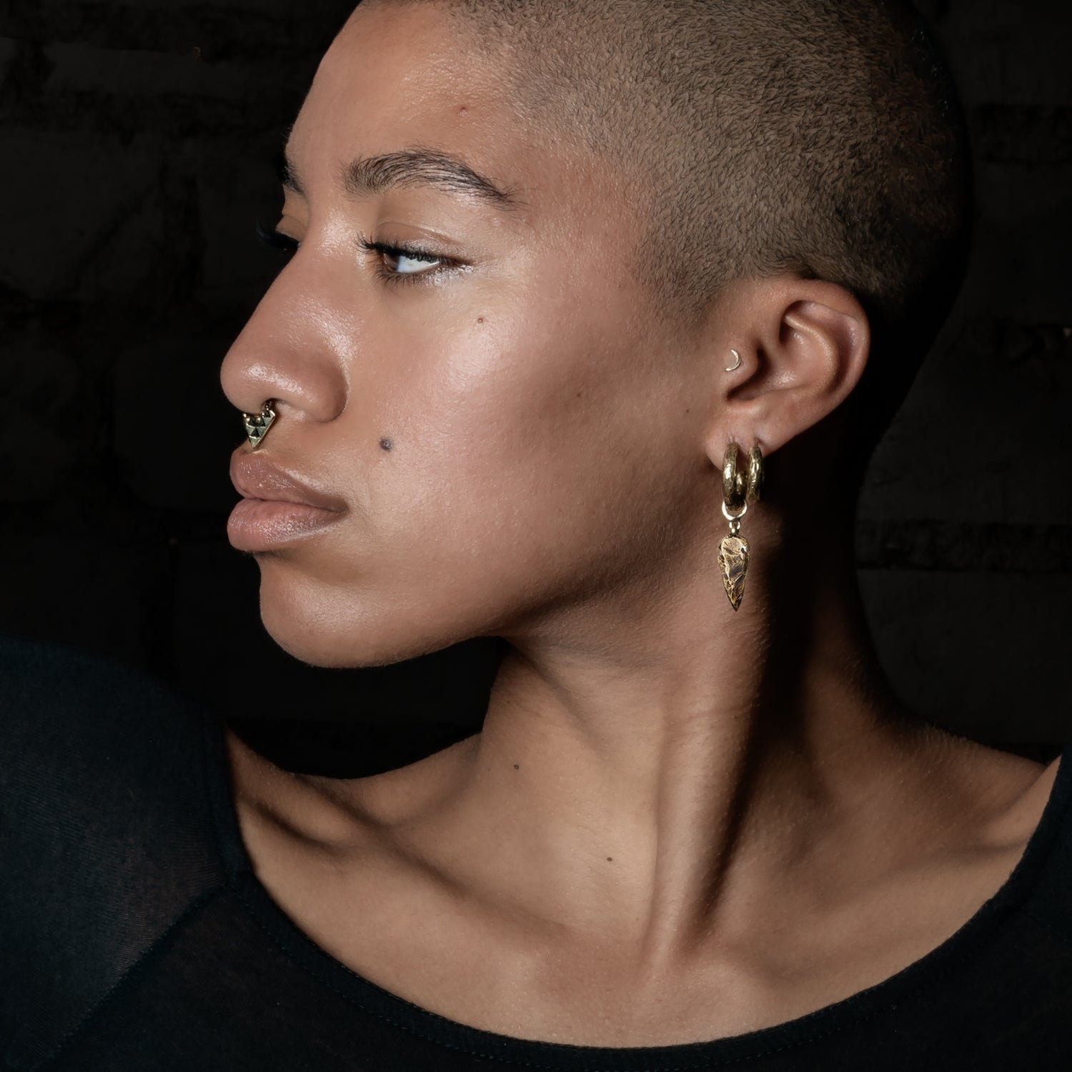 model wearing Arrowhead Brass Clicker Earrings
