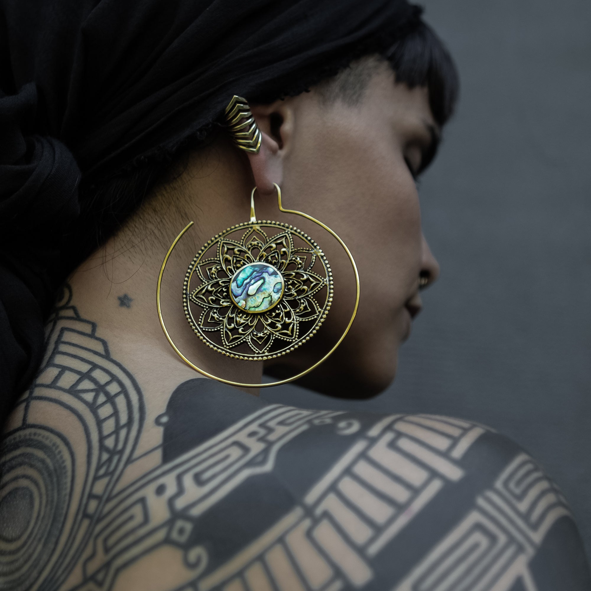 model wearing golden brass large lotus open mandala earrings with centred abalone
