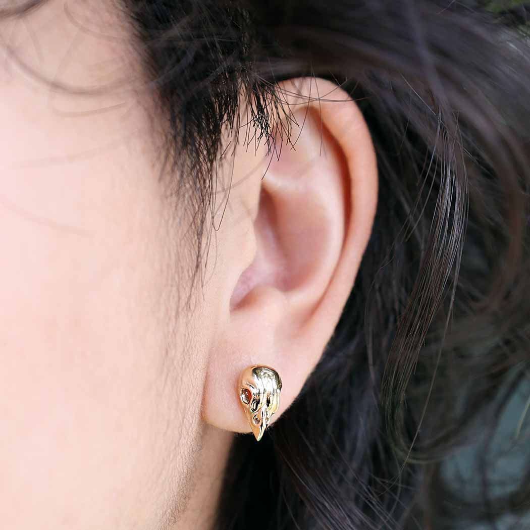 model wearing Bronze Sparrow Skull Stud Earrings