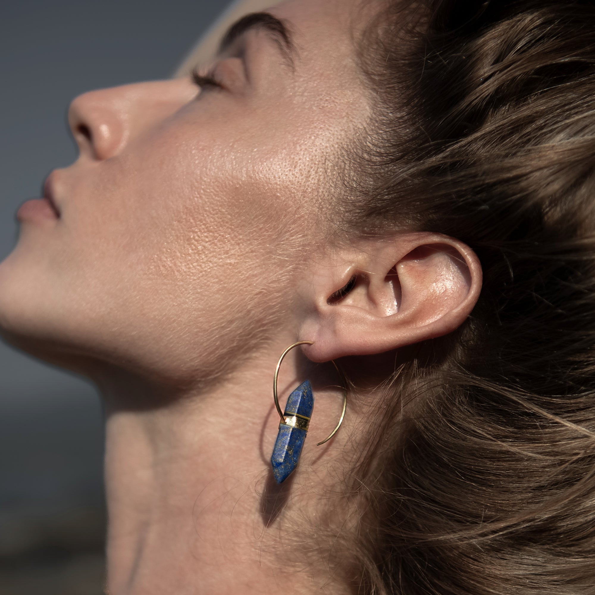model wearing golden Zen open Hoop Earrings with Lapis lazuli