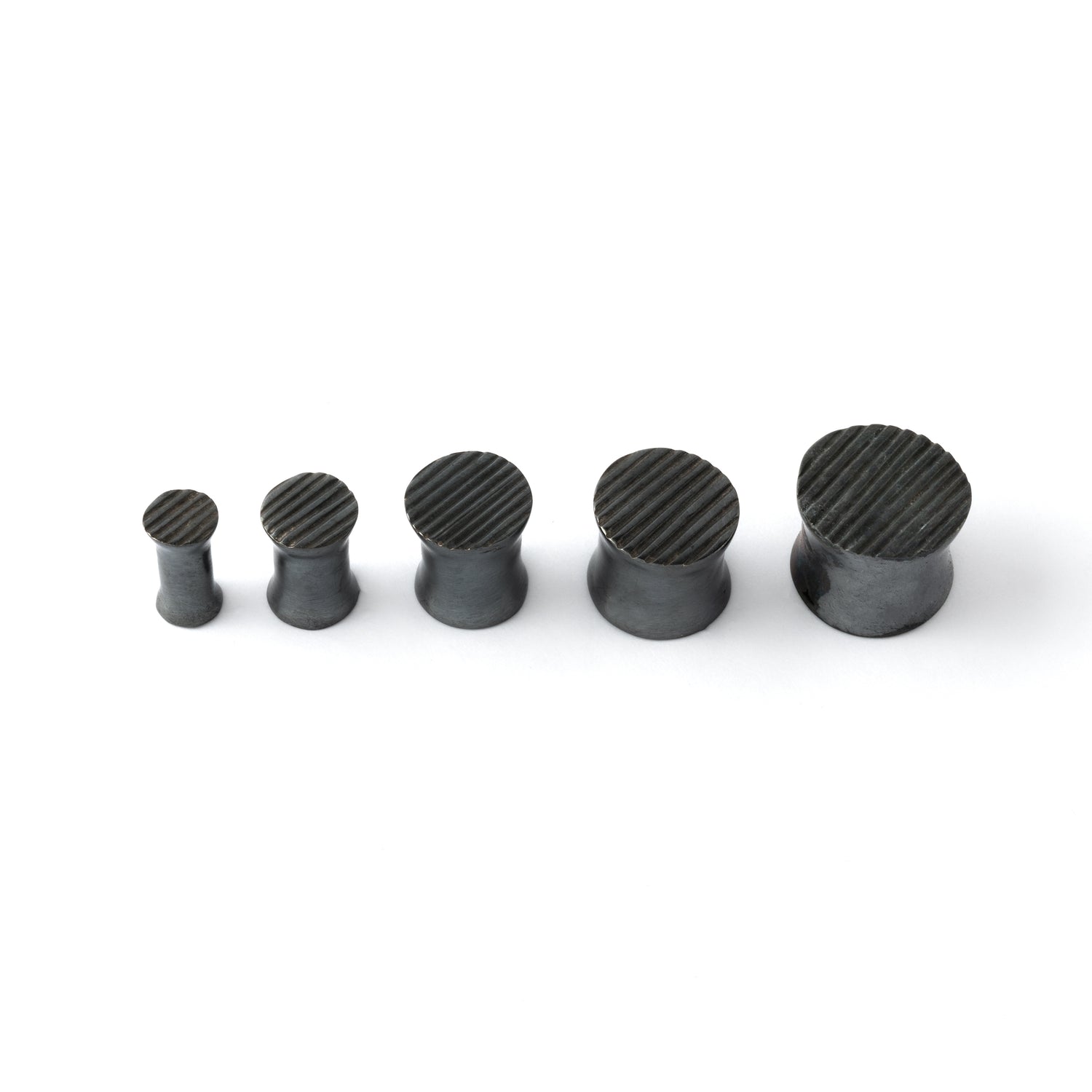 several sizes of double flared black silver scratched ear plugs front view