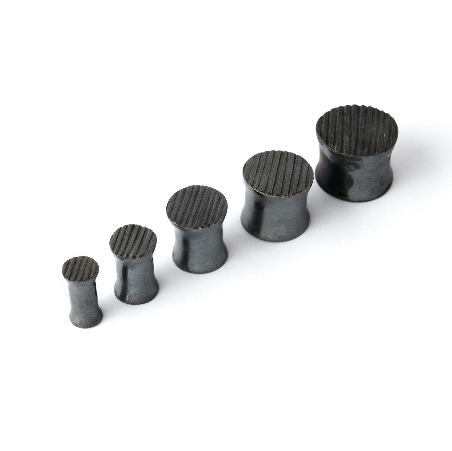 several sizes of double flared black silver scratched ear plugs side view