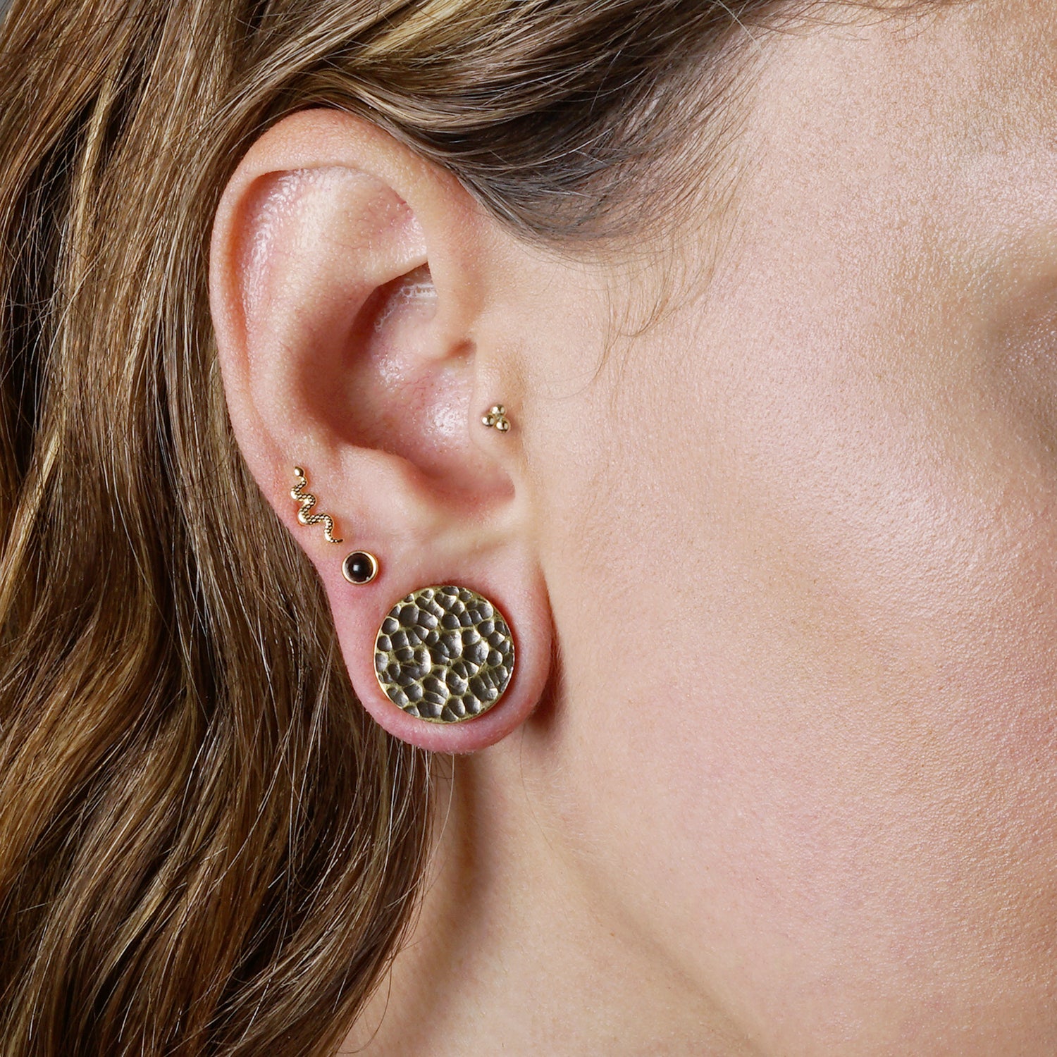 model wearing 14k Gold internally threaded serpent 16g flat back labret stud on her cartilage