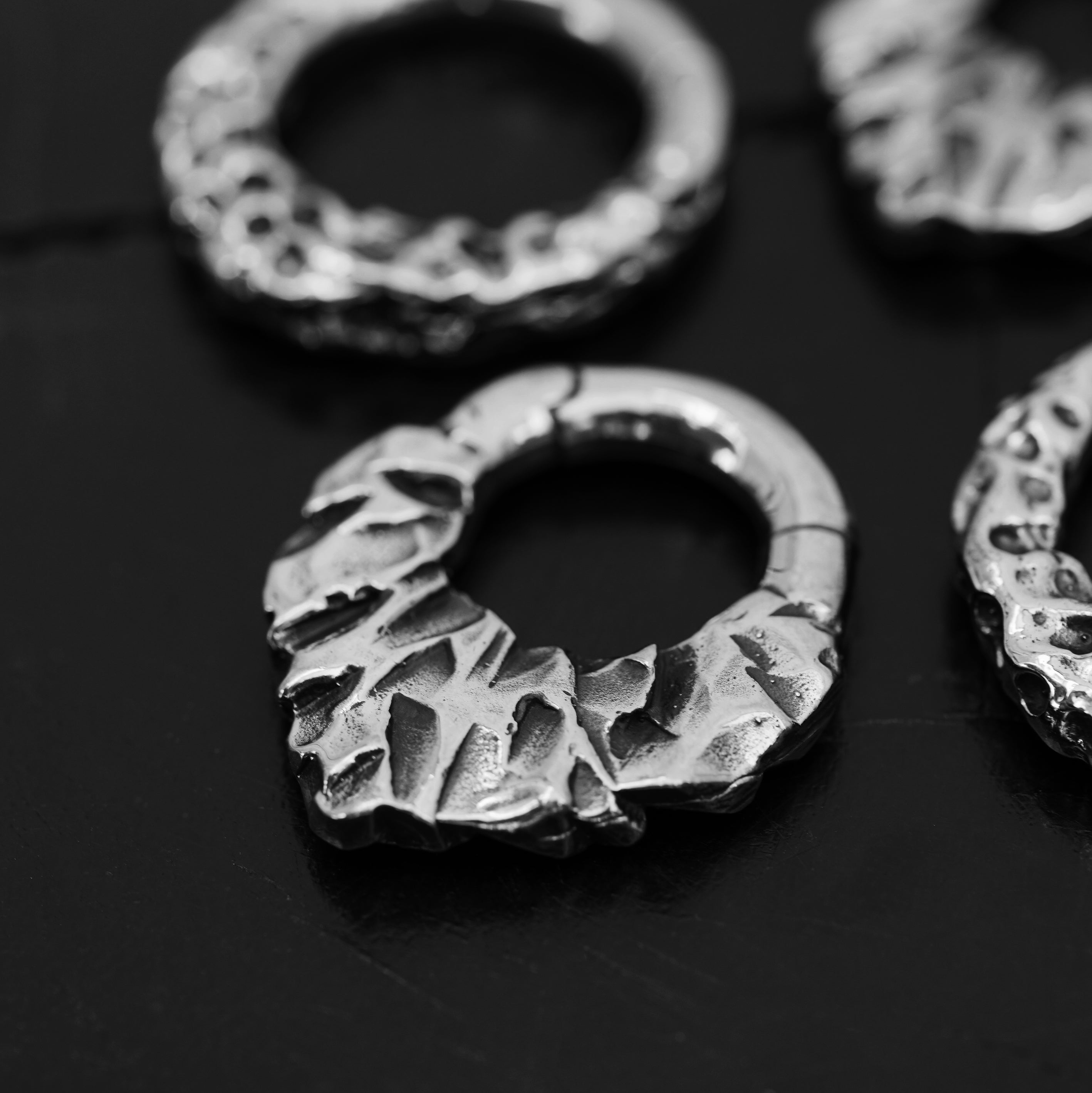single silver brass teardrop shaped ear hoop hanger with rocky texture close up right side view