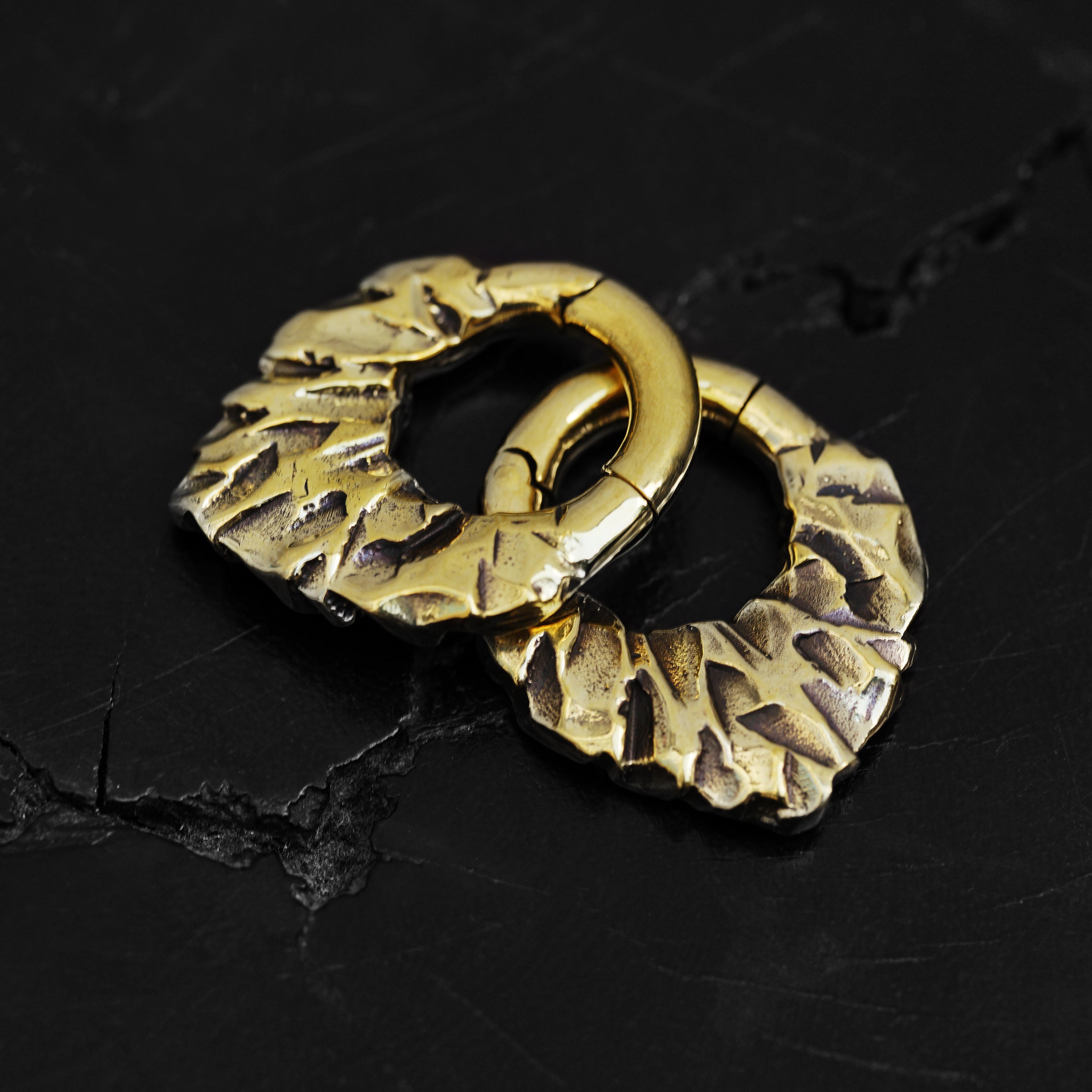 pair of gold brass teardrop shaped ear hoops hangers with rocky texture black background