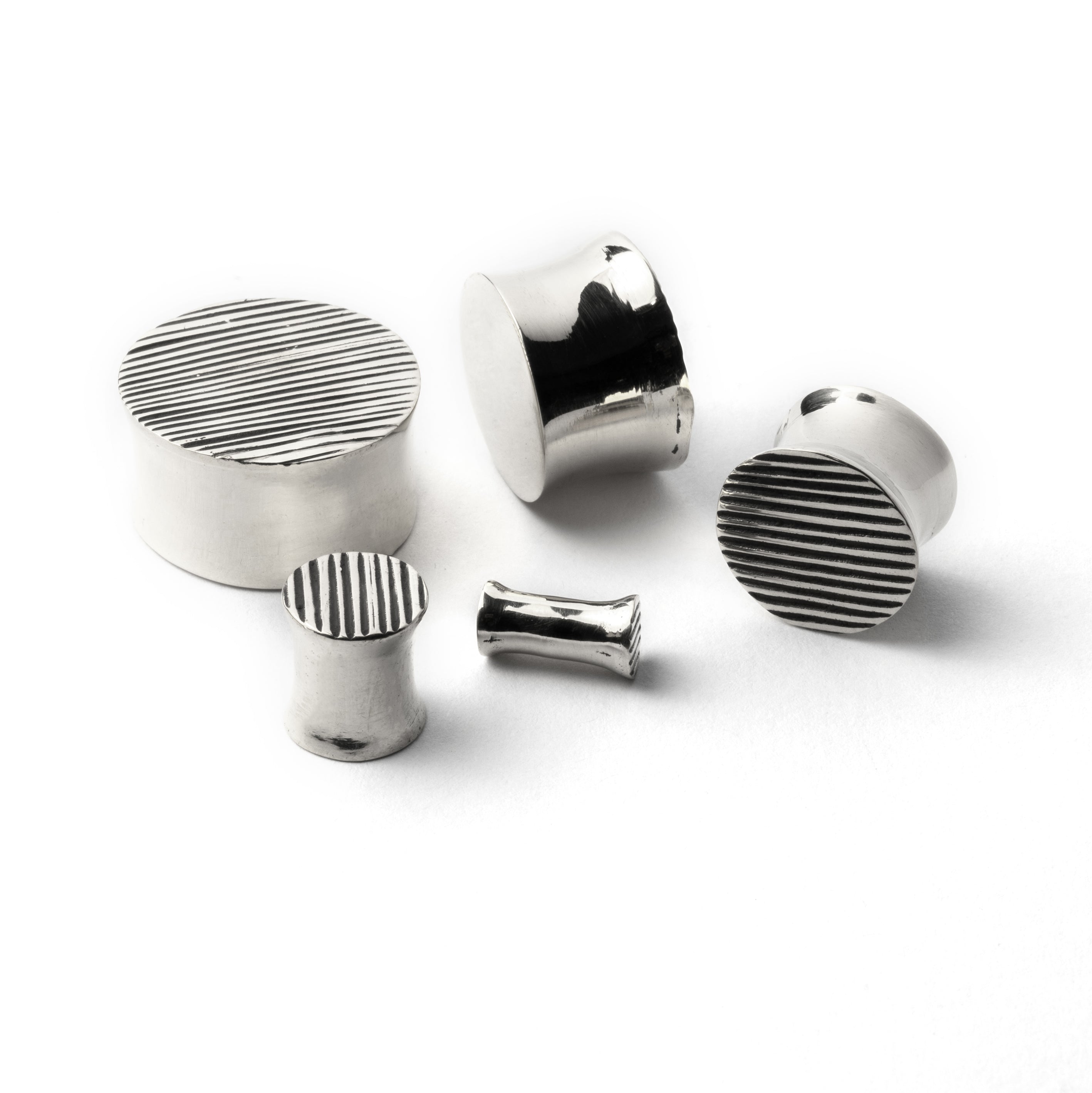 several sizes of scratched double flared ear plugs front and side view