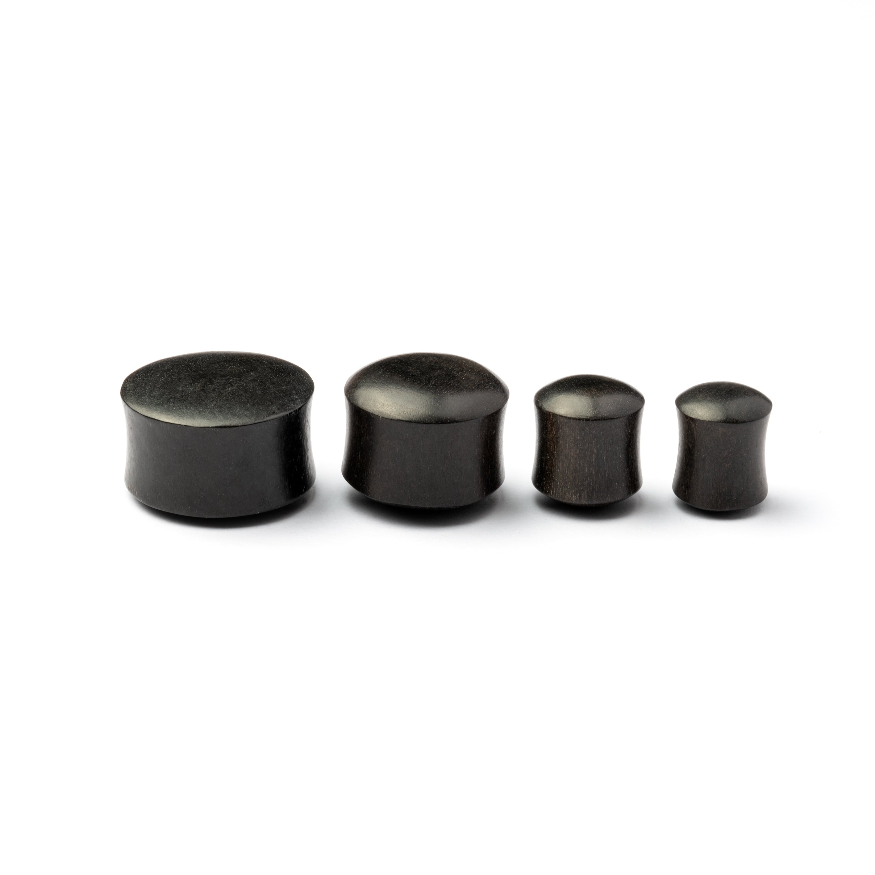 Several sizes of smooth black wood plugs side view