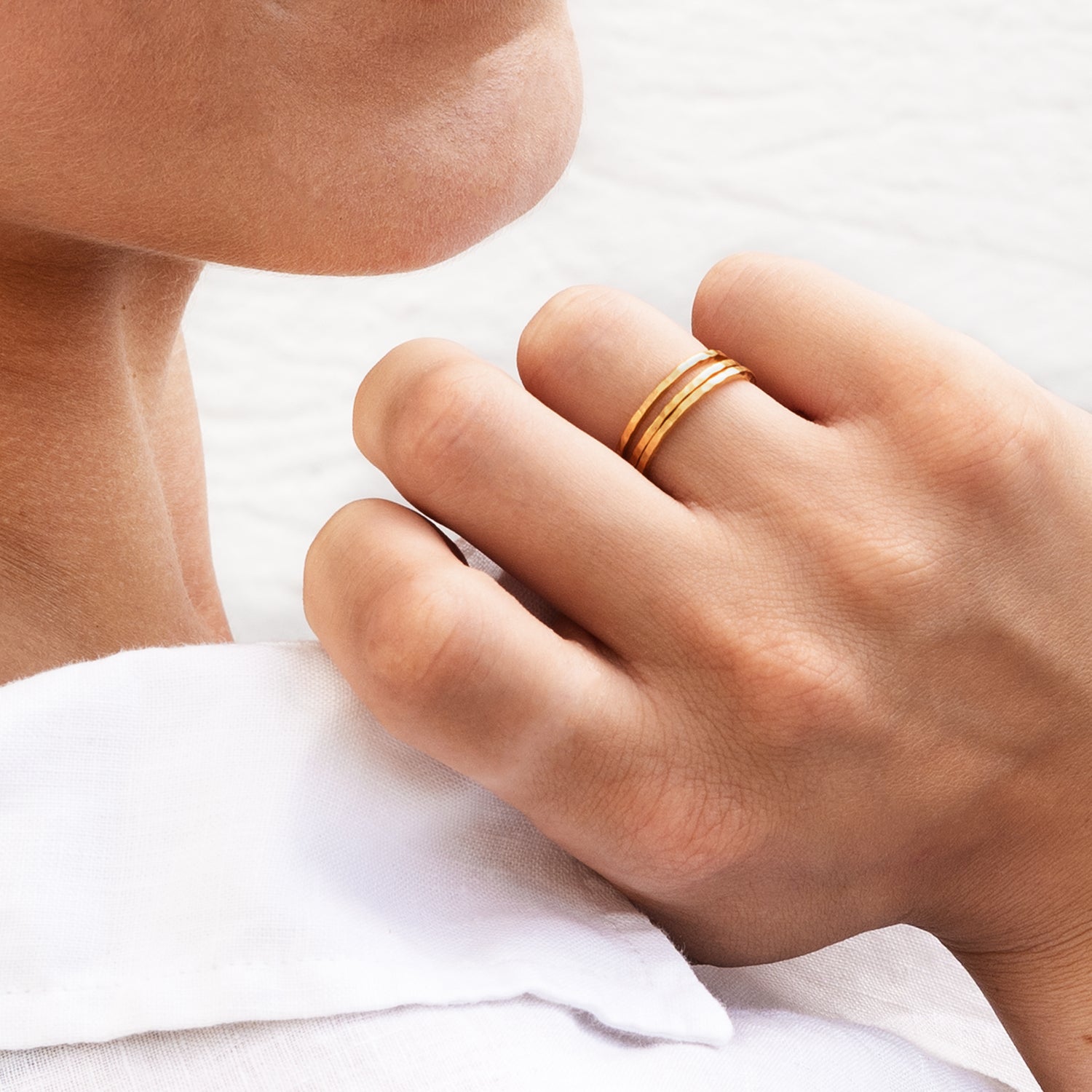 model wearing multiple 24k gold hammered stacking band rings