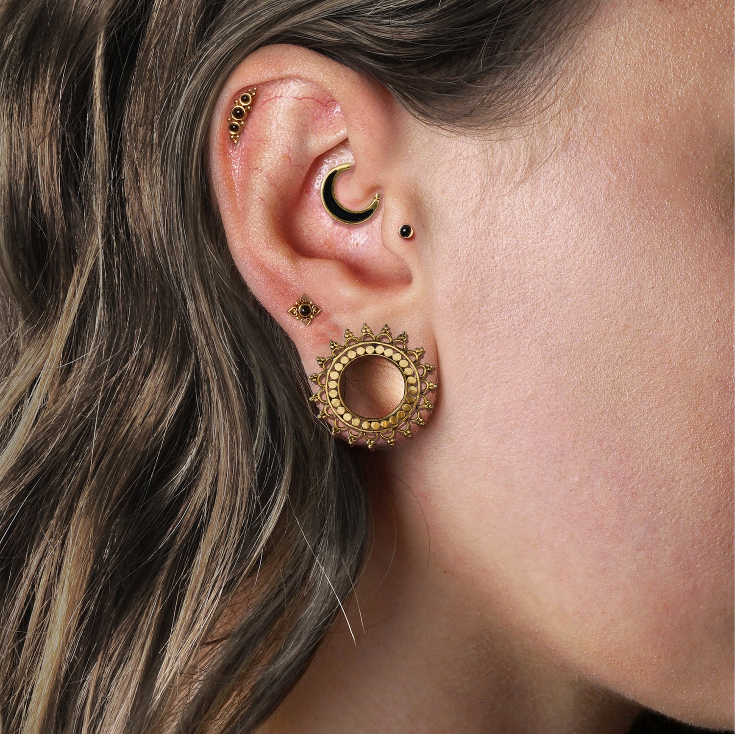 model wearing Tara Tunnels, deva labret on her cartilage, Aanya Black Shell piercing ring on her daith, Neptune Golden Labret with Onyx on her upper lobe, Golden Labret with Onyx on her traus