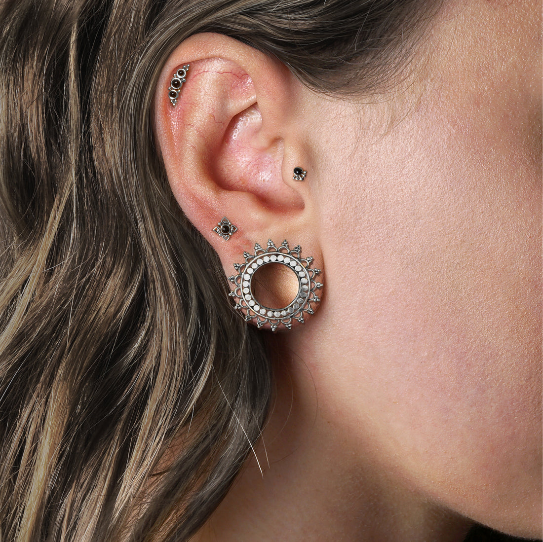 model wearing silver Tara Tunnels, deva labret on her cartilage, Neptune Golden Labret with Onyx on her upper lobe, Layla Golden Labret with Onyx on her traus