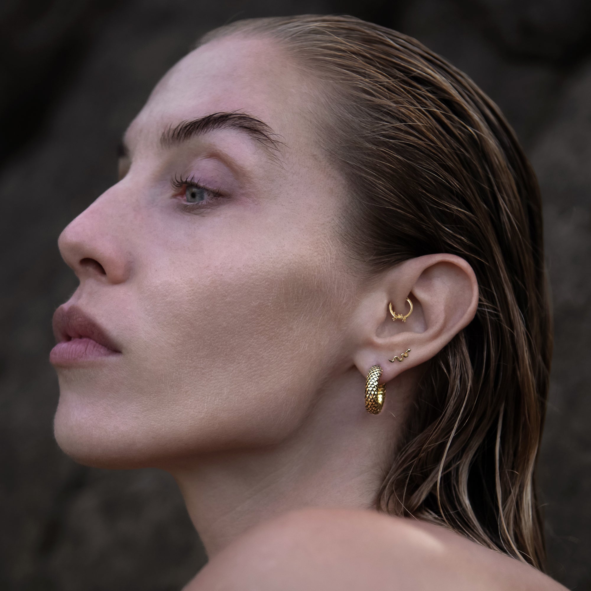 model wearing 14k Gold internally threaded serpent 16g flat back labret stud on her lobe