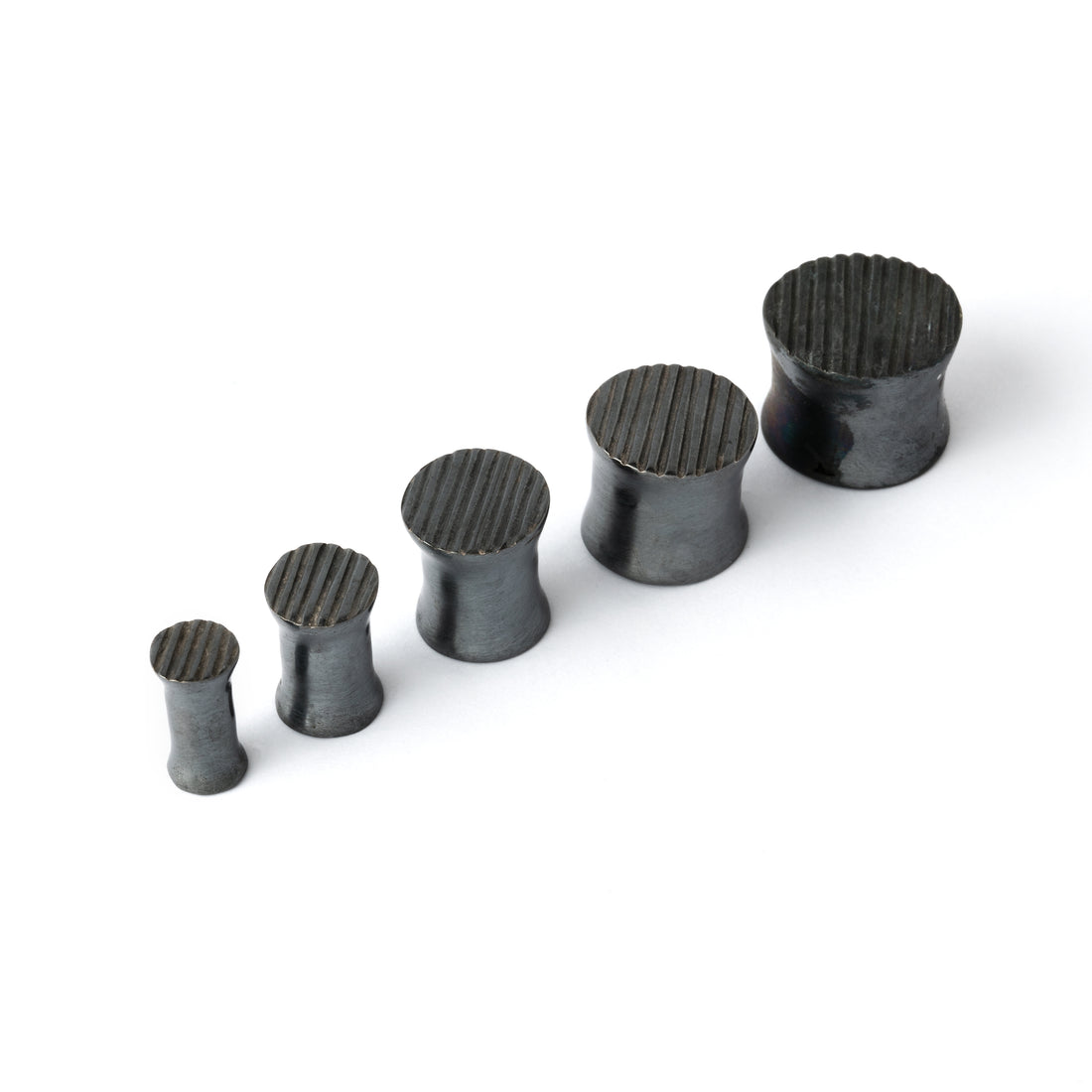 several sizes of double flared black silver scratched ear plugs side view