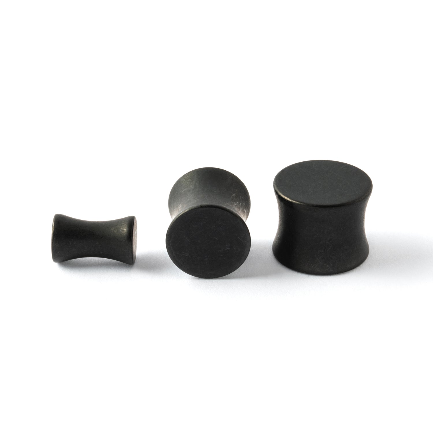 several sizes of surgical steel black steel plugs with double flared ends side and front view
