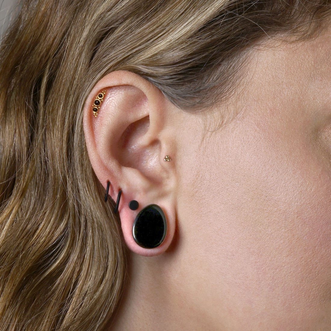 model wearing black Agate teardrop stone plug