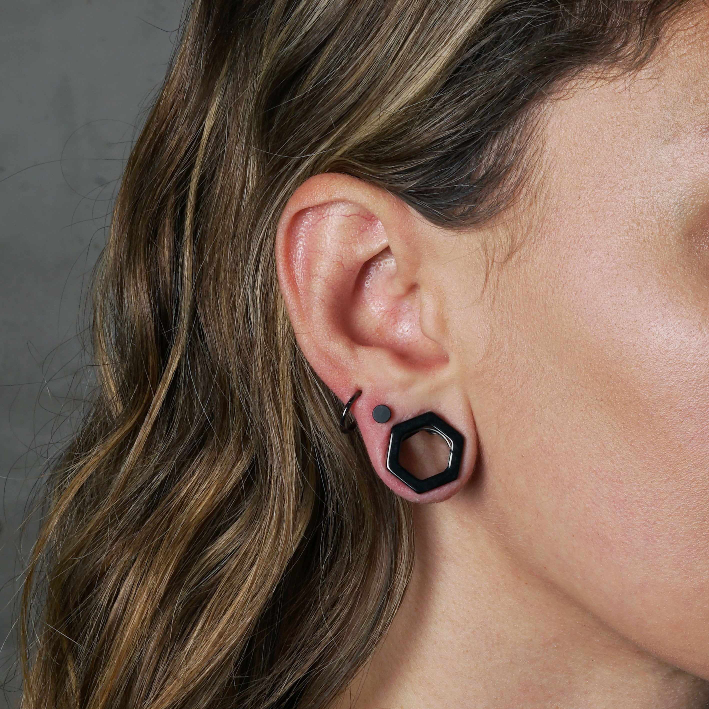 model wearing surgical steel black hexagon ear tunnel