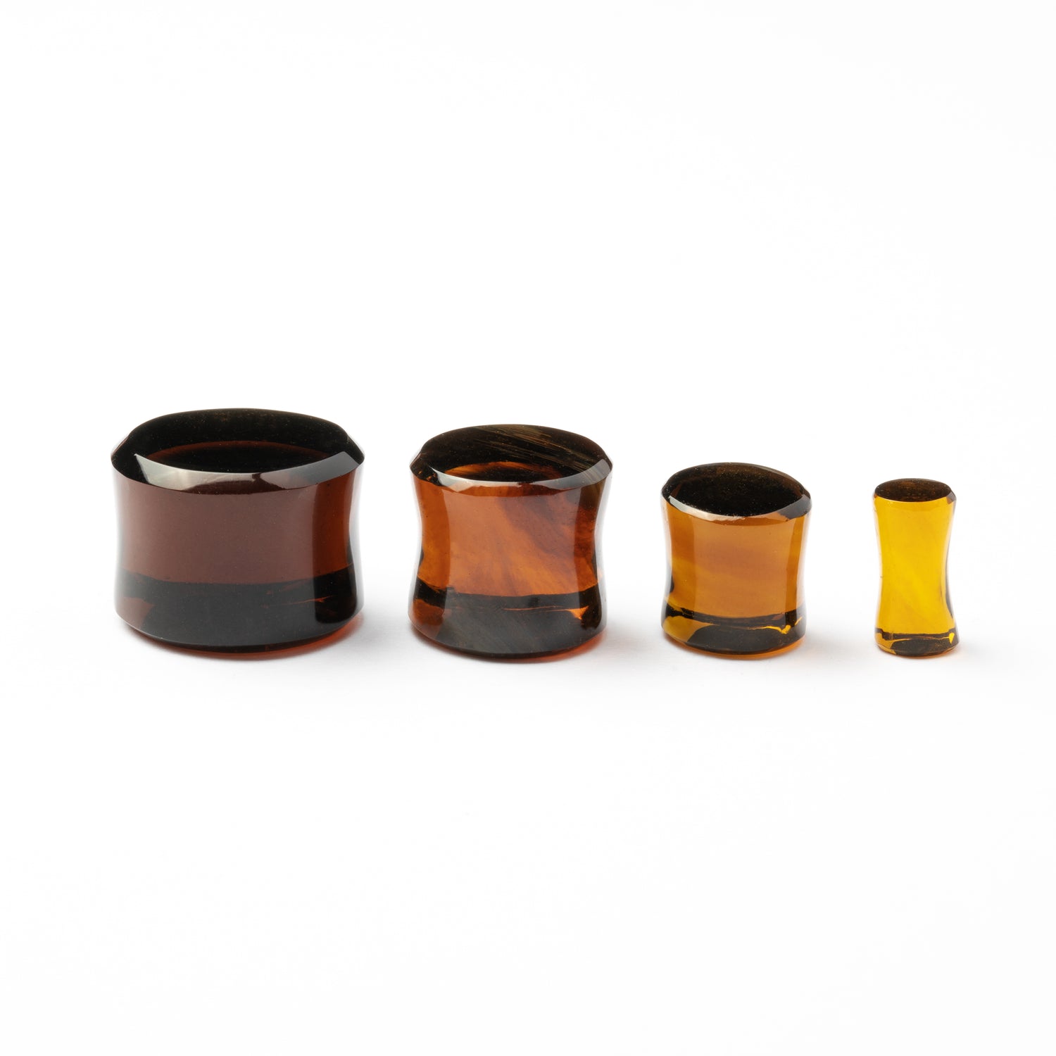 several sizes of Brown Volcanic Glass double flare ear plugs side view