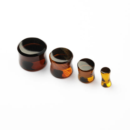      several sizes of Brown Volcanic Glass double flare ear plugs side front view