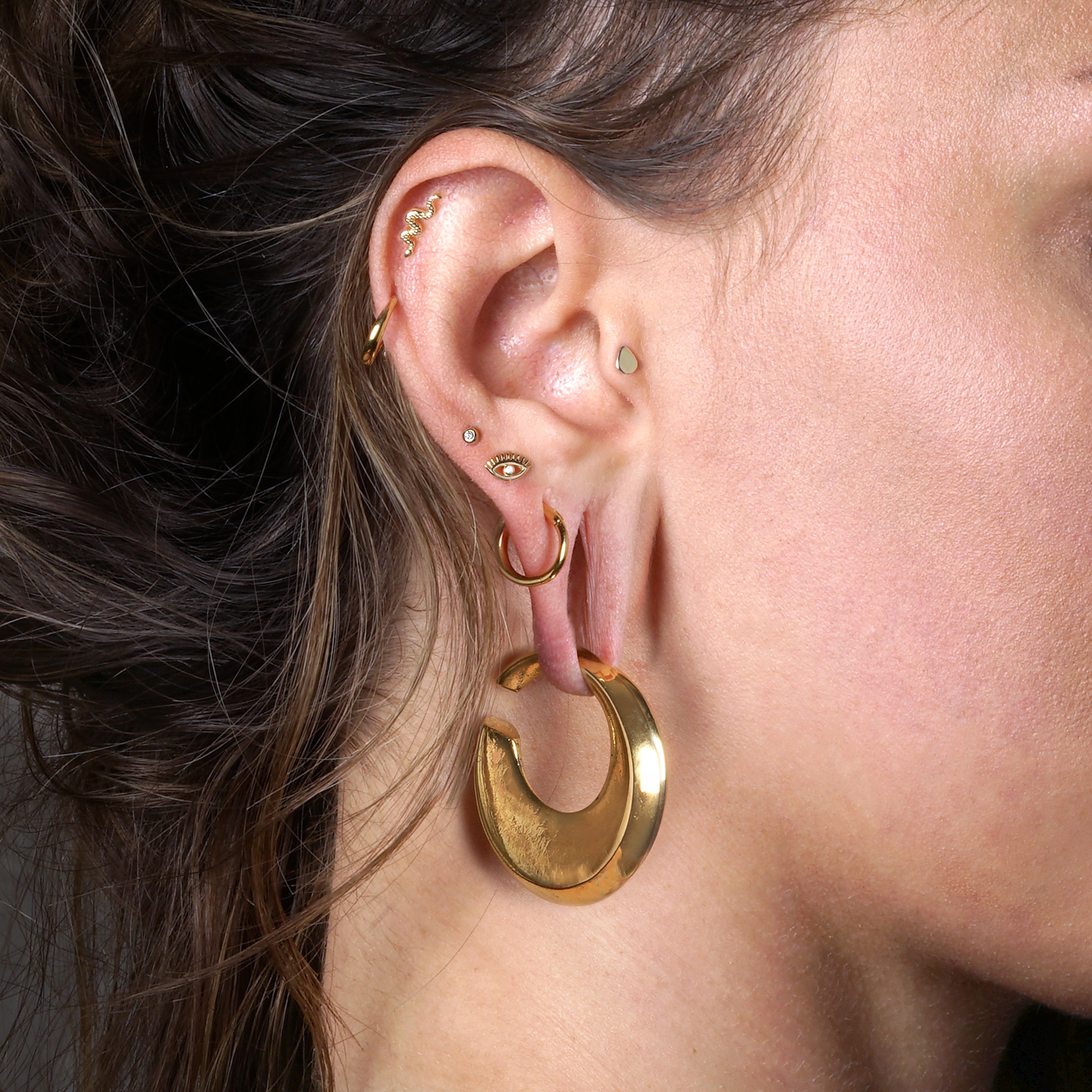 model wearing 14k Gold internally threaded screw back earring 1.2mm (16g), 8mm, evil eye labret with centred cz on her upper lobe