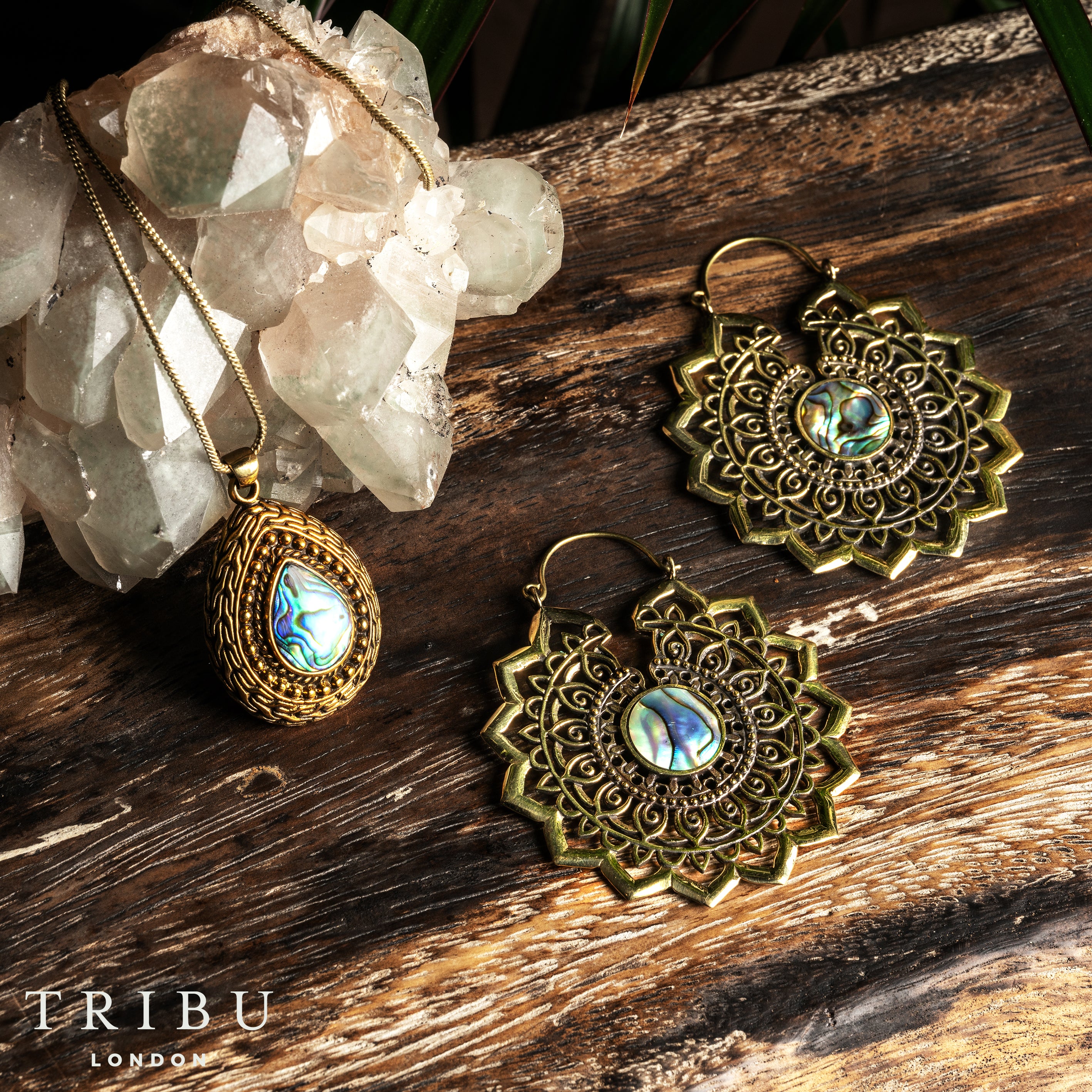 pair of golden brass large lotus open mandala earrings with centred abalone with a matching pendant on wood