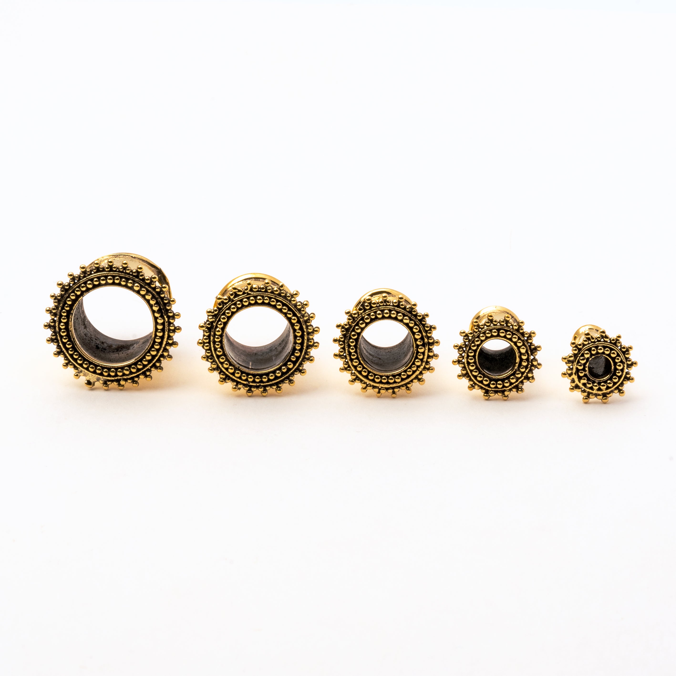 several sizes of golden brass Indian ear tunnel front view
