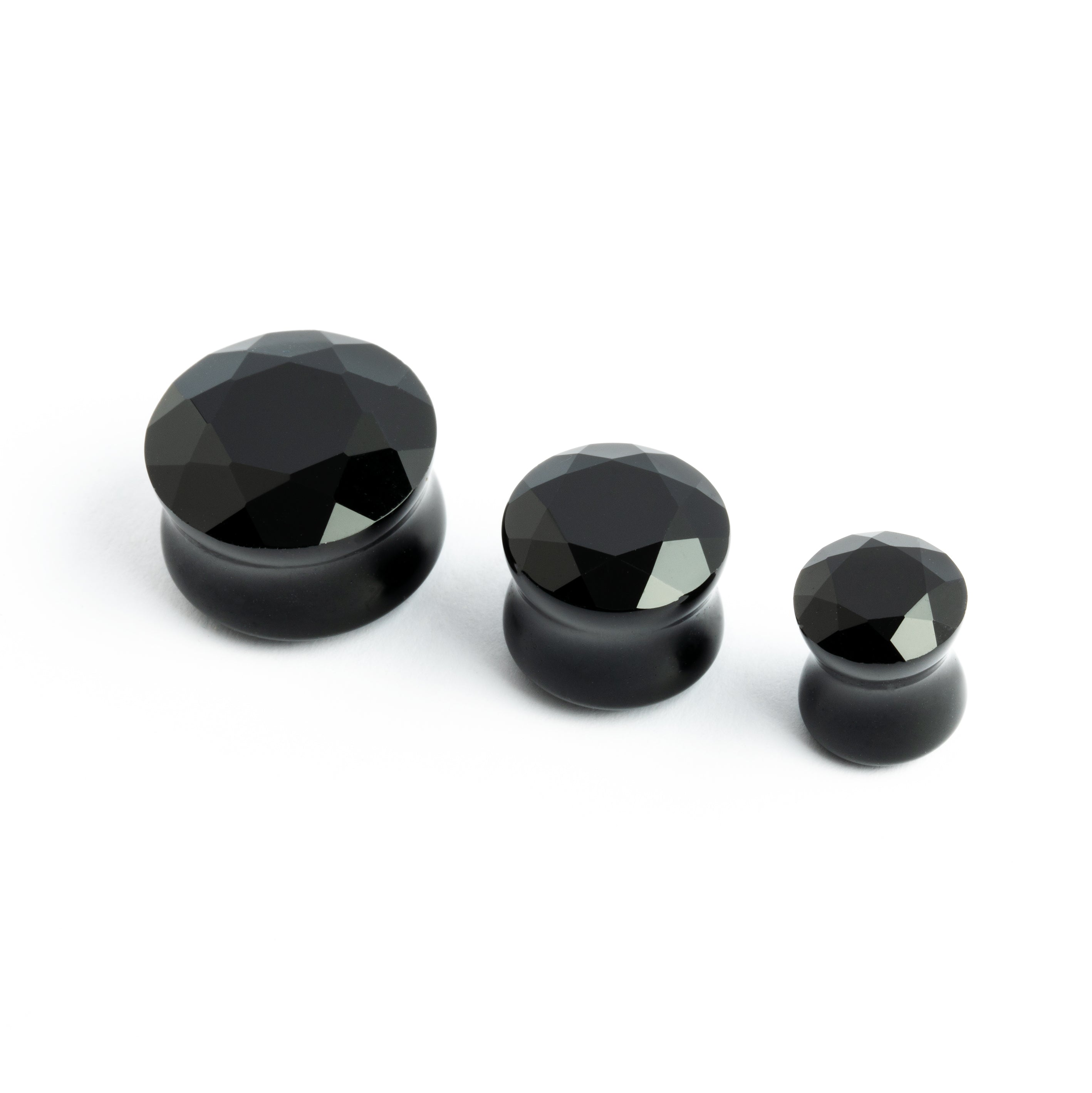 several sizes of faceted black onyx ear plugs front view
