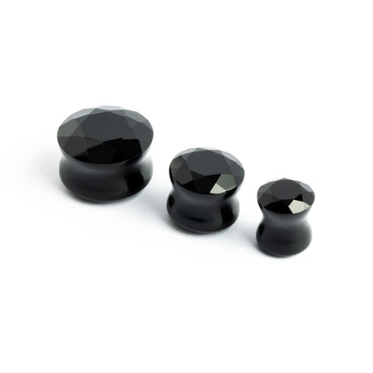several sizes of faceted black onyx ear plugs side view