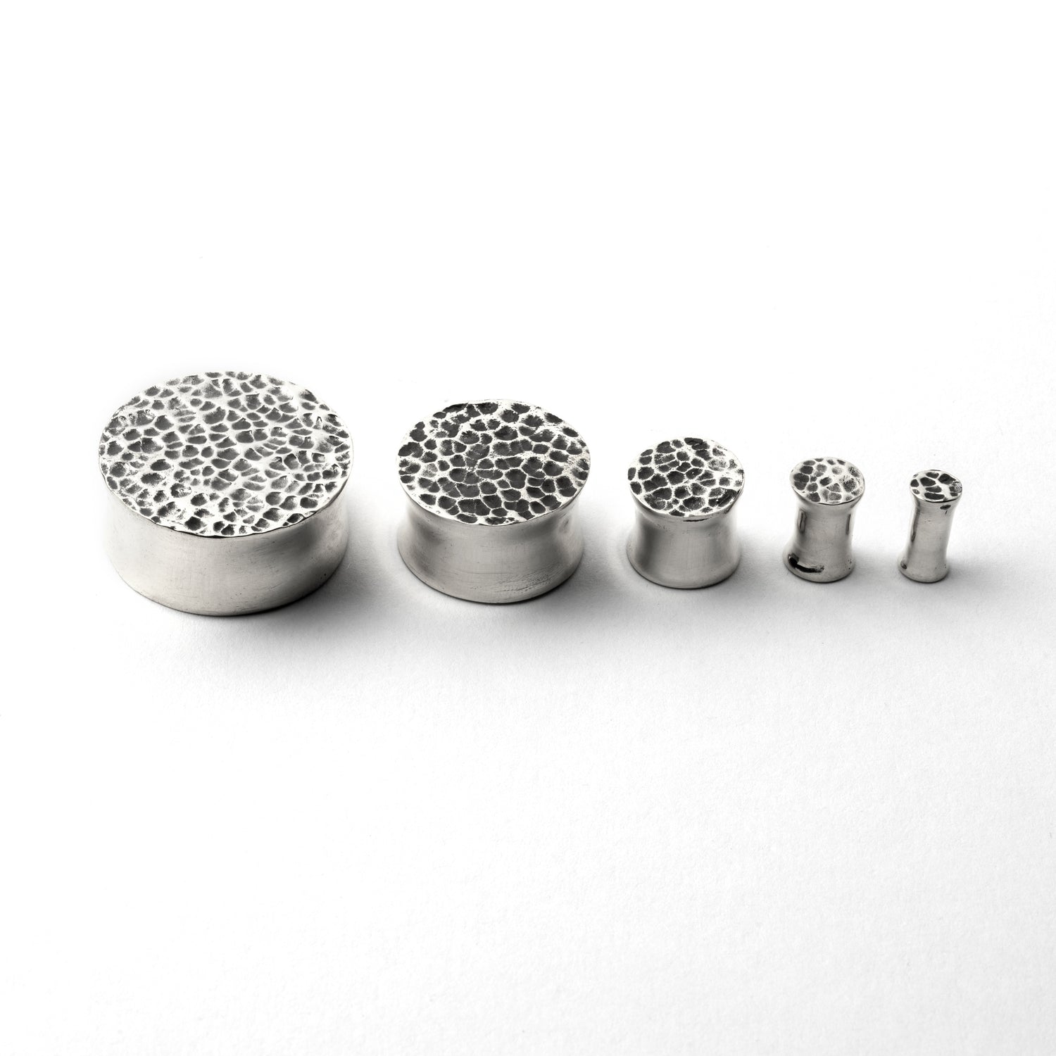 several sizes of hammered silver double flared ear plugs side front view