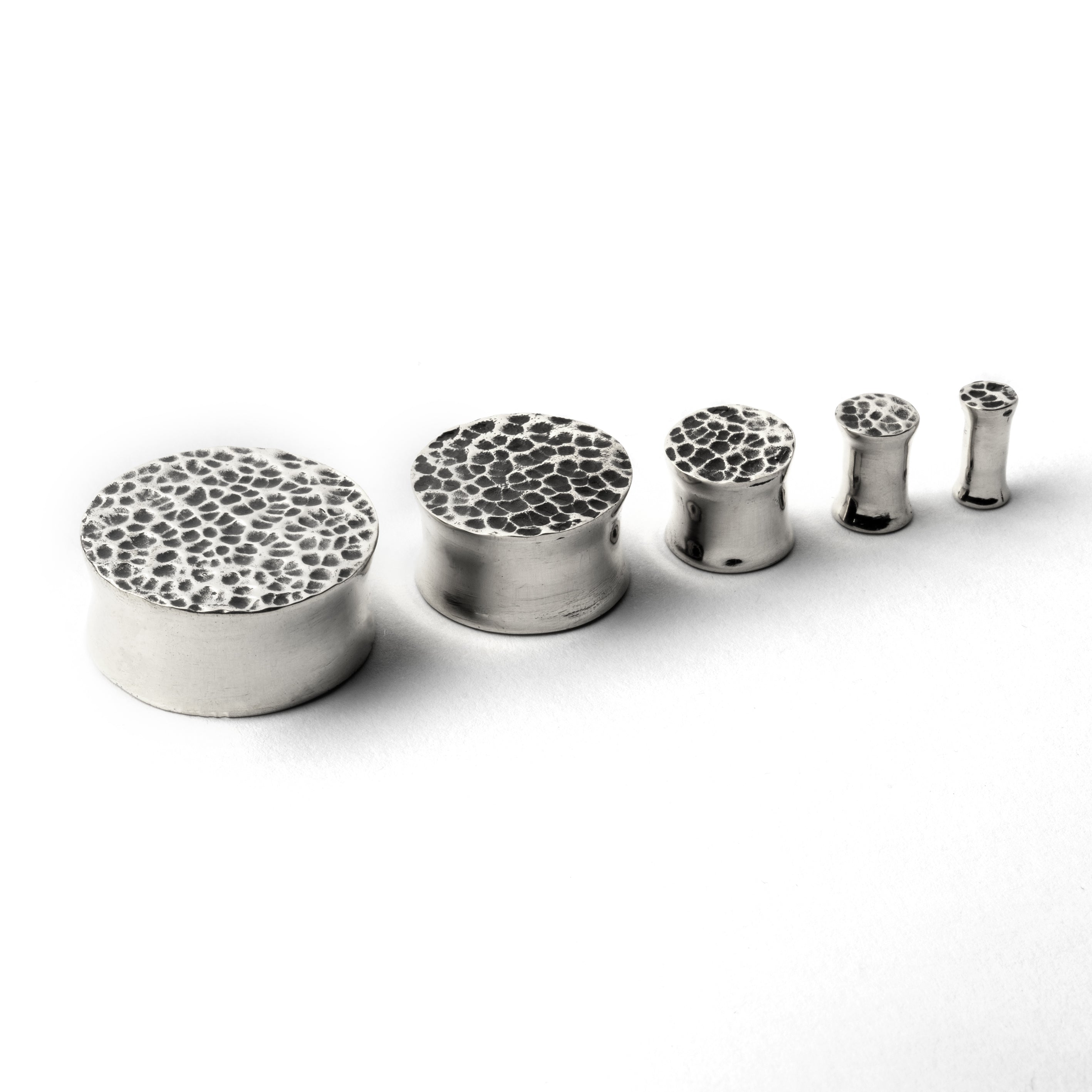 several sizes of hammered silver double flared ear plugs side front view