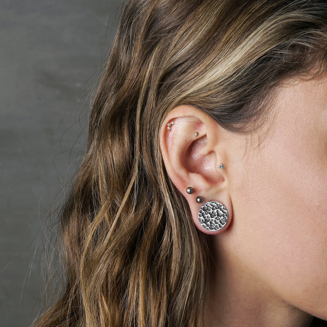 model wearing hammered silver plug