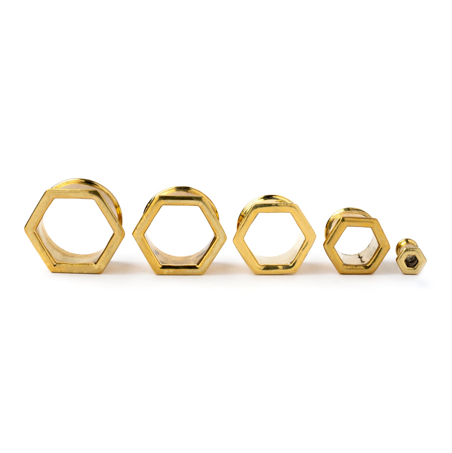 several sizes of golden brass hexagon ear tunnels front view