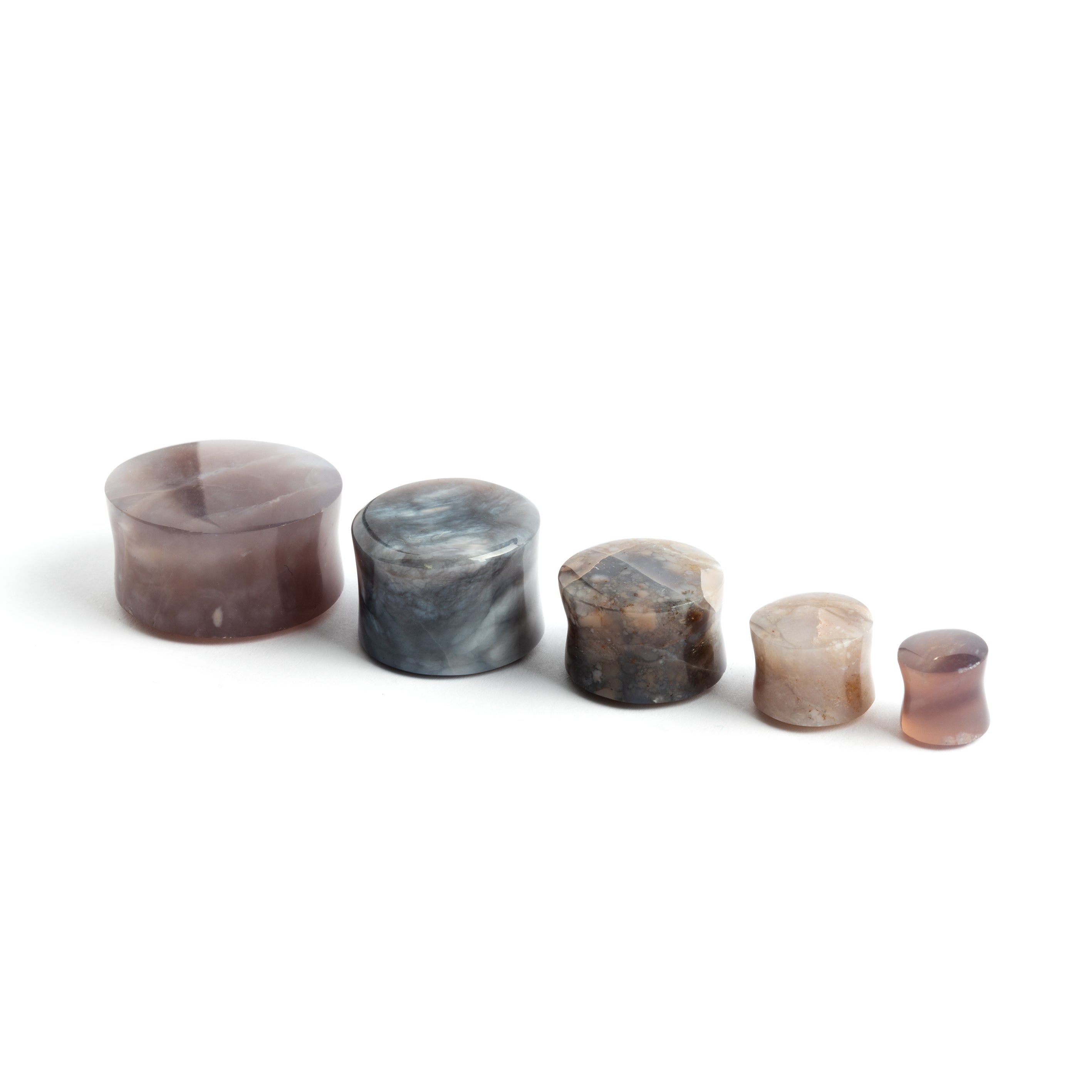 several sizes of lavender double flare stone ear plugs side view