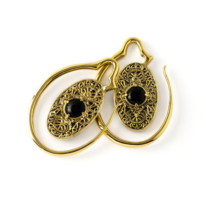 pair of golden large ear weights hangers oval shaped with intricate filigree pattern an black onyx