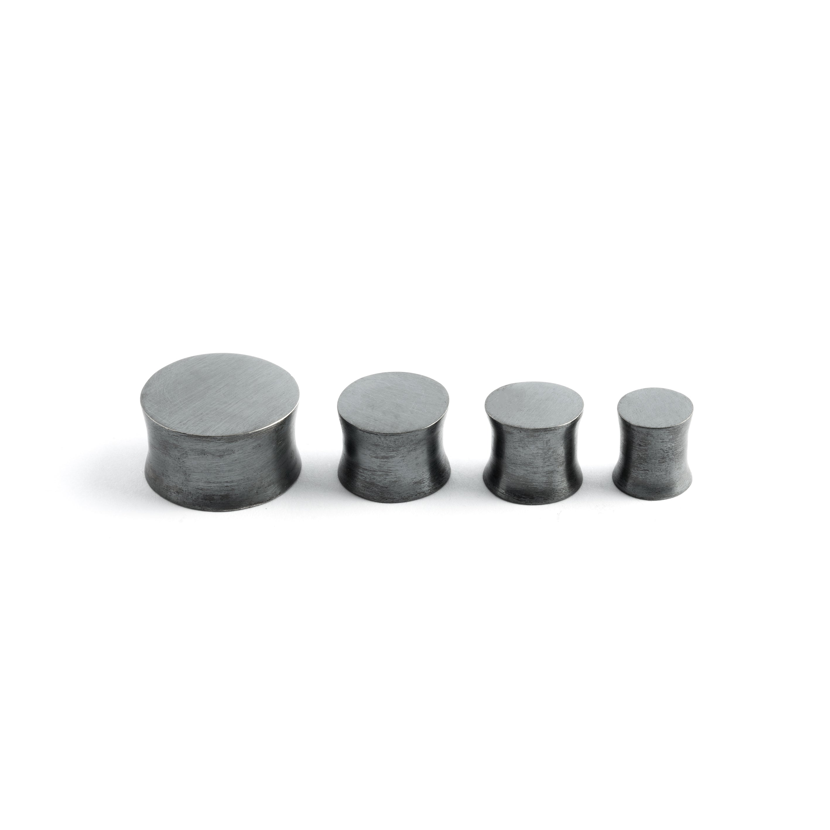 several sizes of double flared black silver ear plugs side view