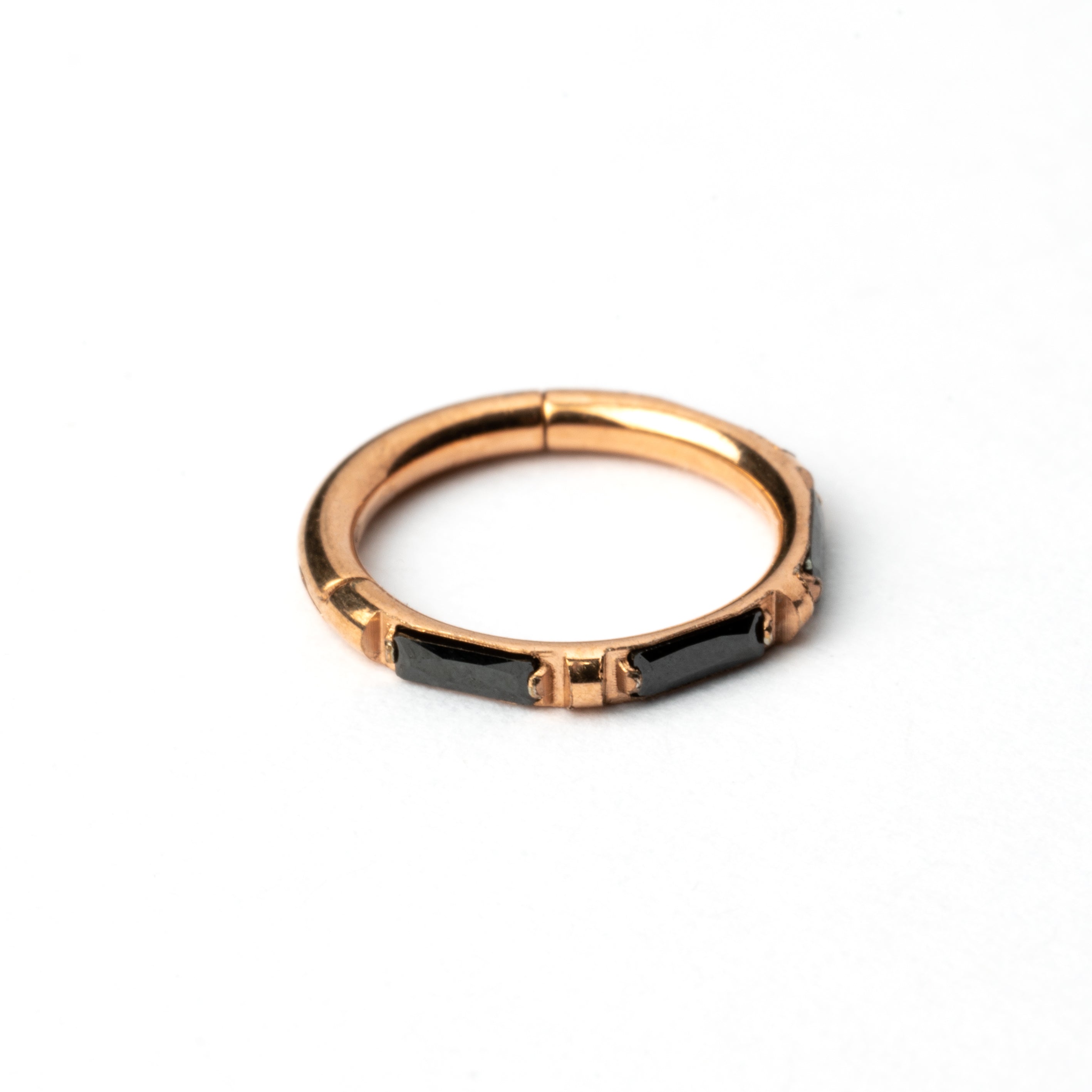 Rose Gold septum clicker with black onyx stones around its rim frontal view