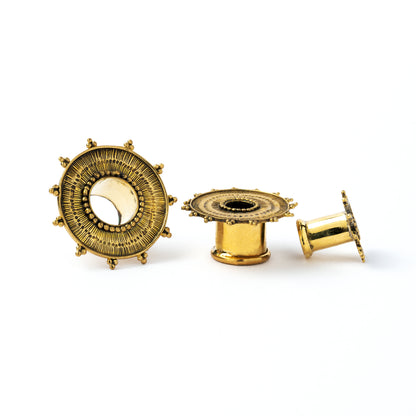 several sizes of Rustic sun golden brass ear tunnels for stretched ears front and side view