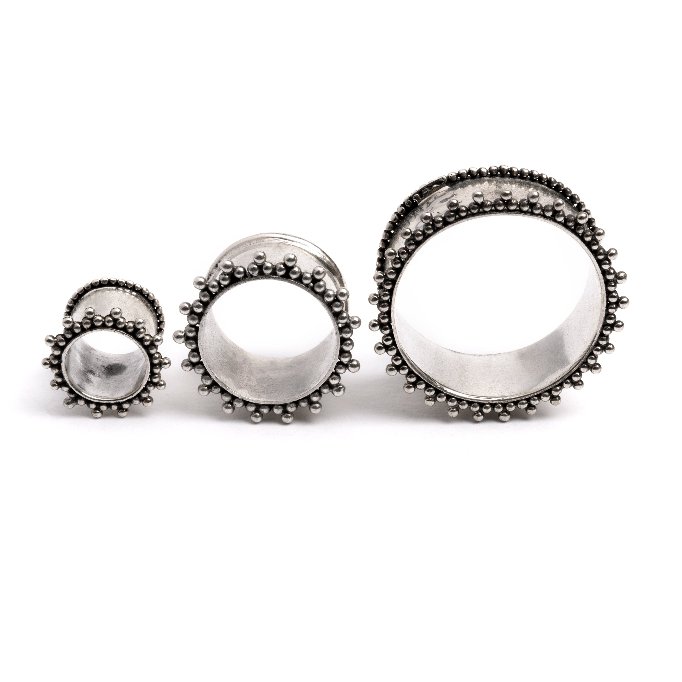 several sizes of double flared silver ear tunnels with tiny spheres front view