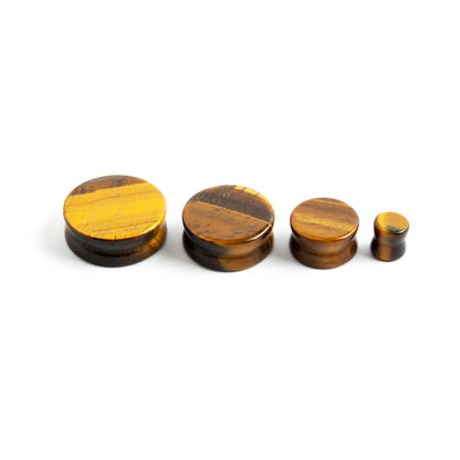 several sizes of tiger eye double flare stone ear plugs side view