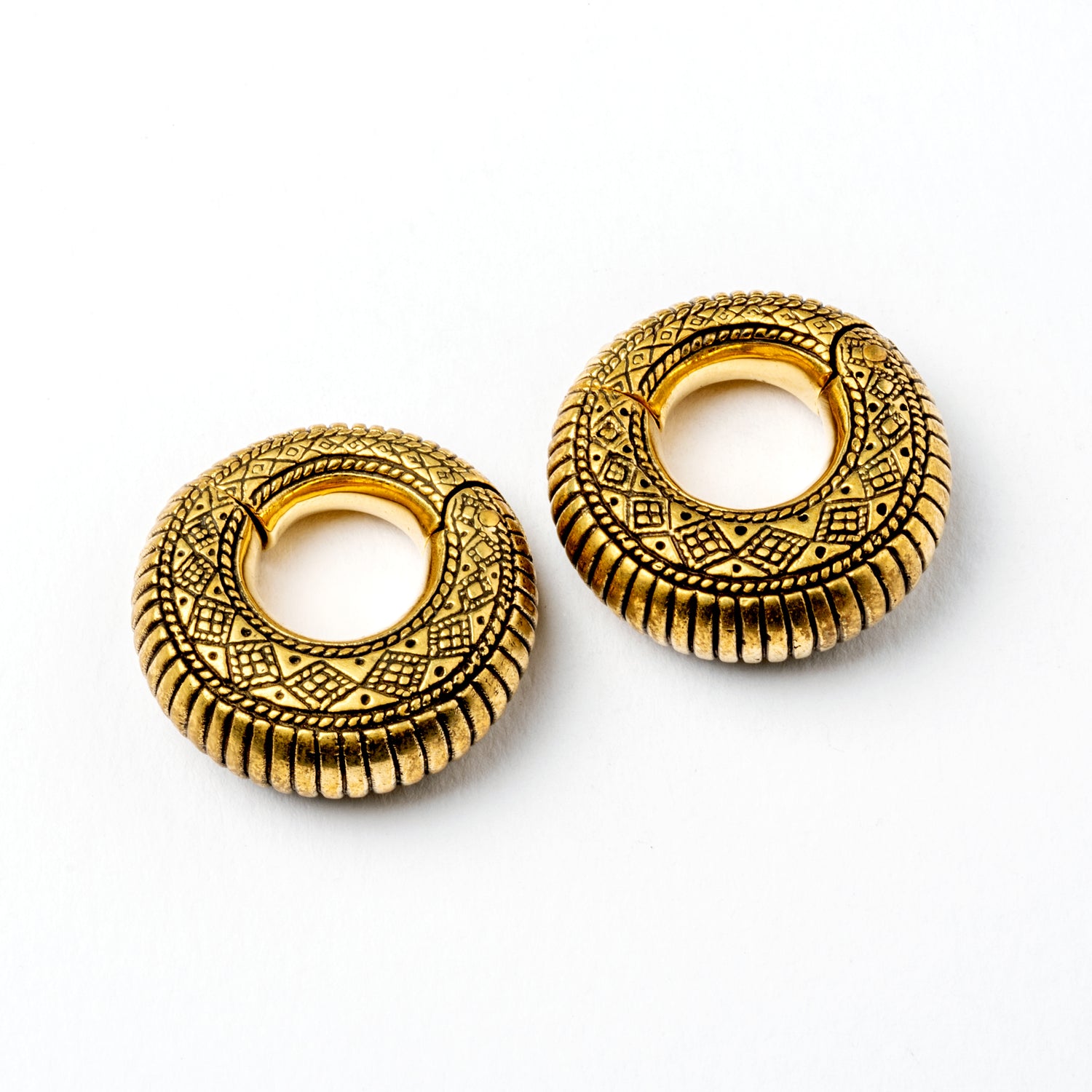 pair of gold brass ear weights hoops with geometric tribal engraved pattern right frontal view