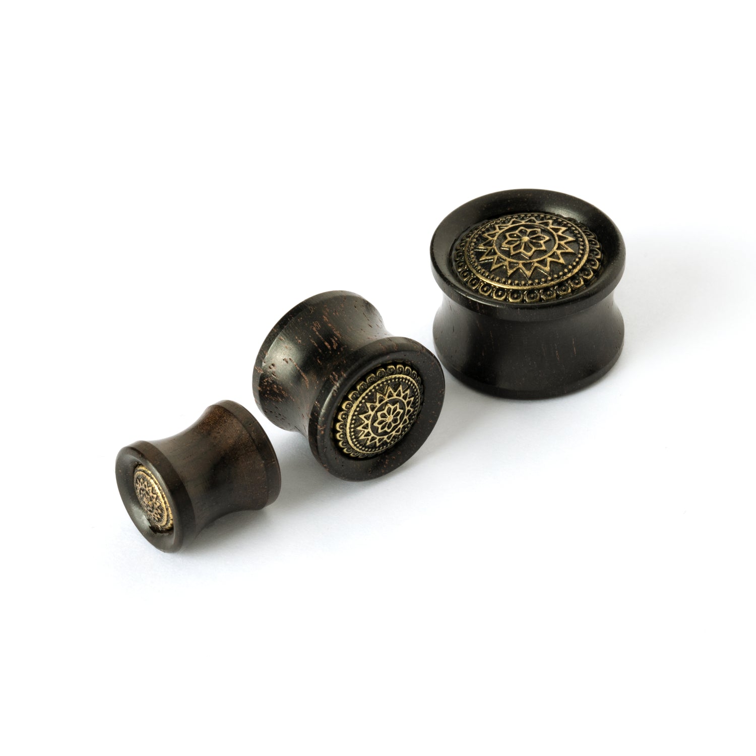 different sizes of ebony wood ear plugs with brass tribal flower ornament