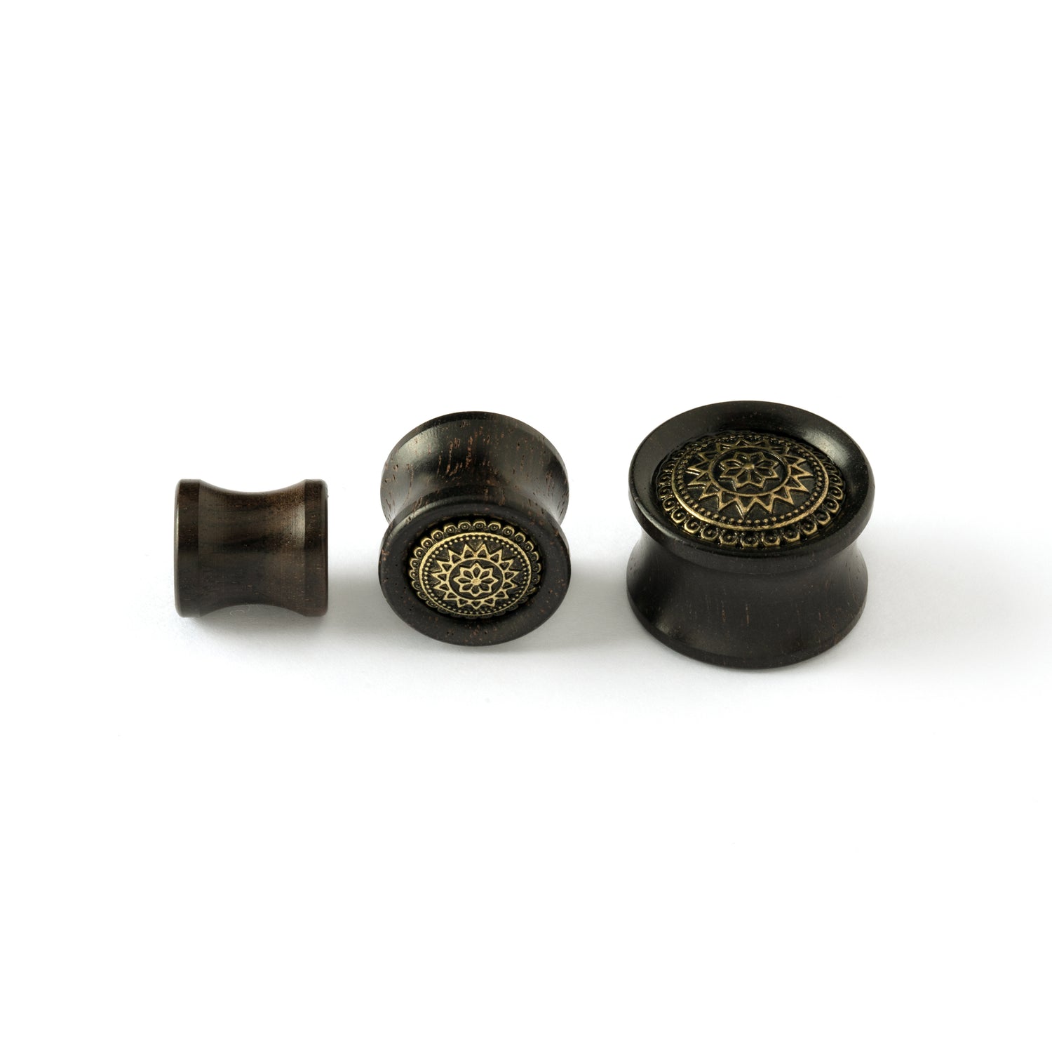 different sizes of ebony wood ear plug with brass tribal flower ornament frontal view