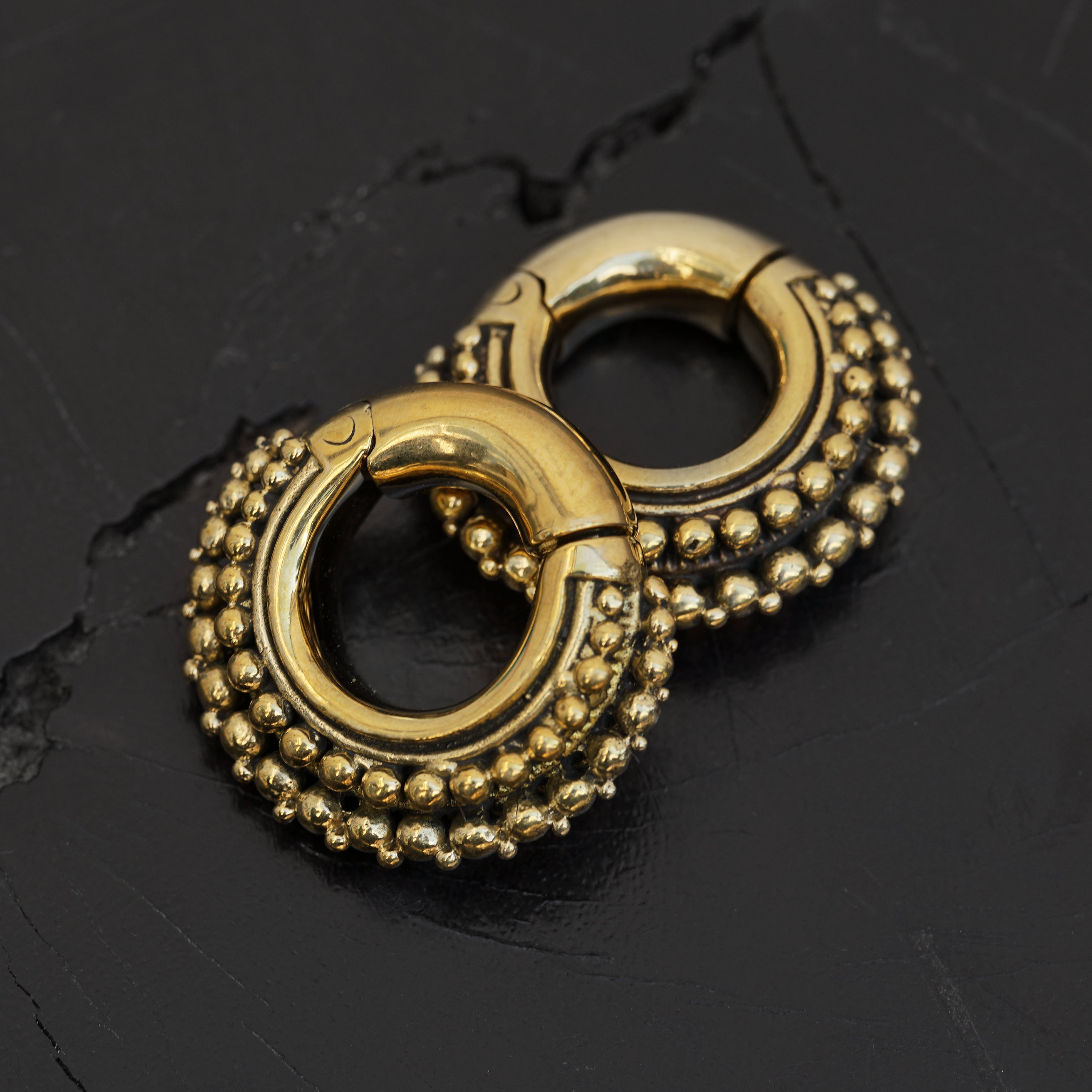 pair of gold brass chunky tribal ear weights hoops black background