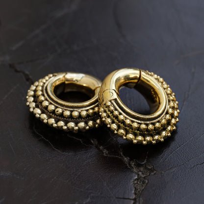 pair of gold brass chunky tribal ear weights hoops side black background view 