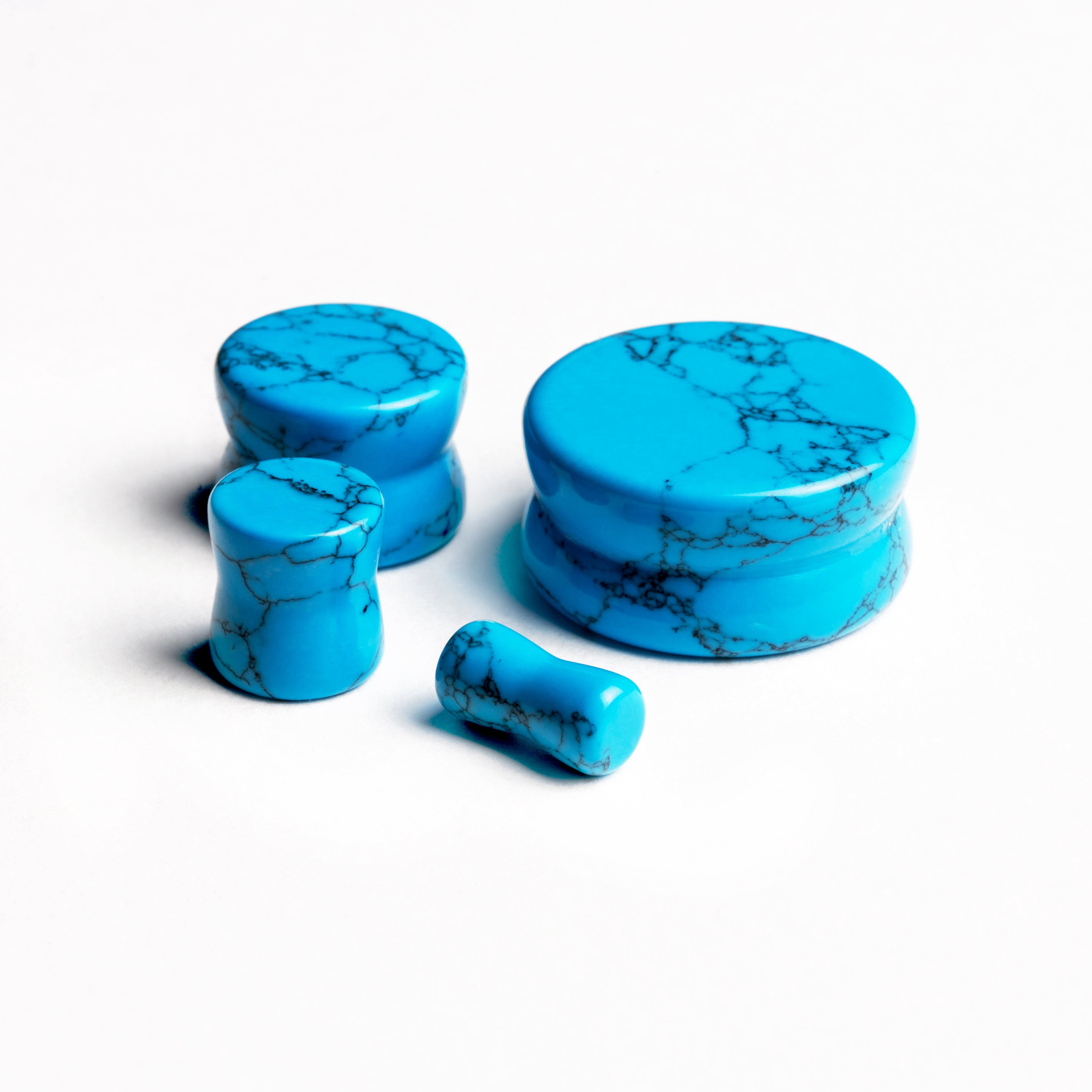 several sizes of turquoise double flared stone ear plugs all sides view