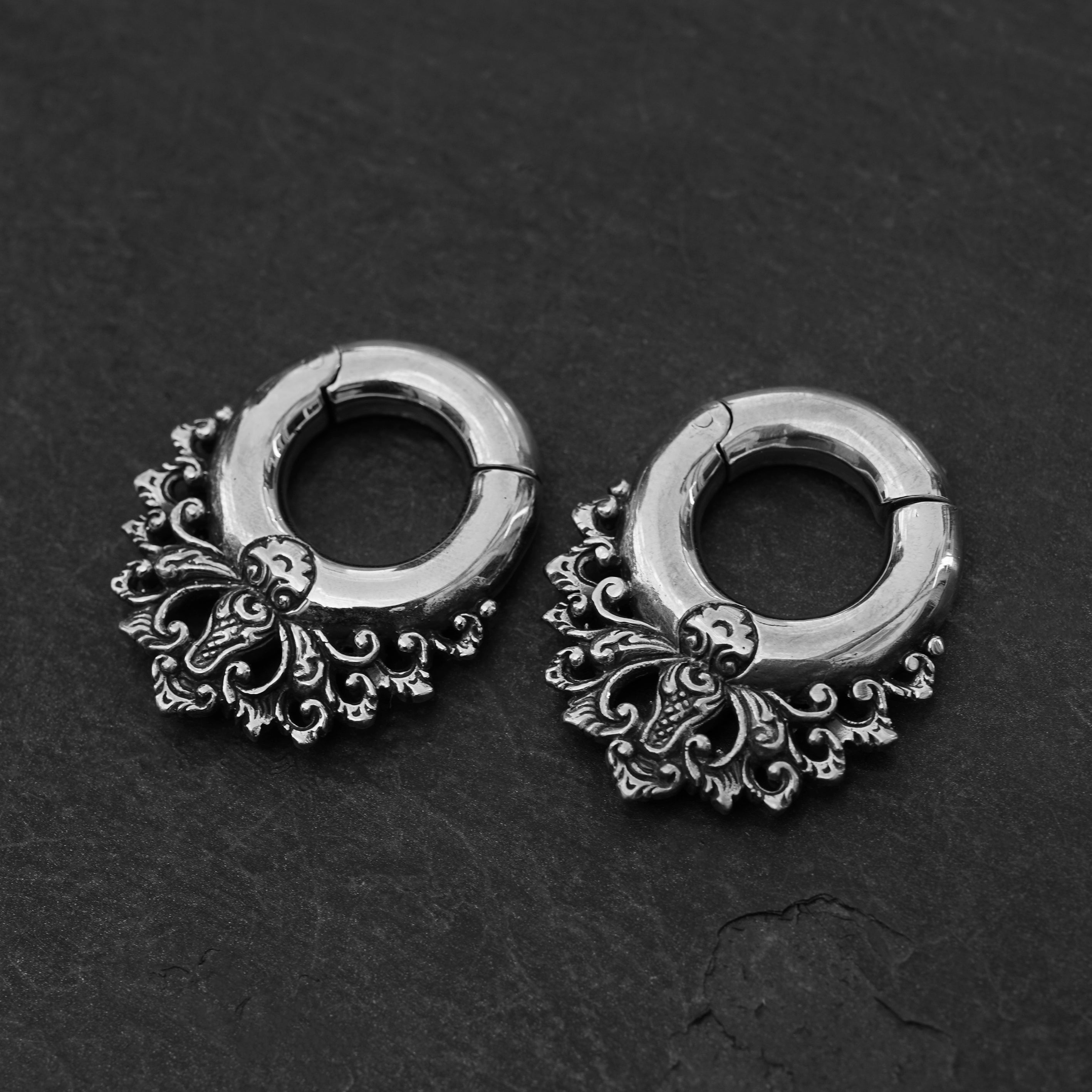 pair of silver brass ear hangers hoops with floral victorian design frontal view black background
