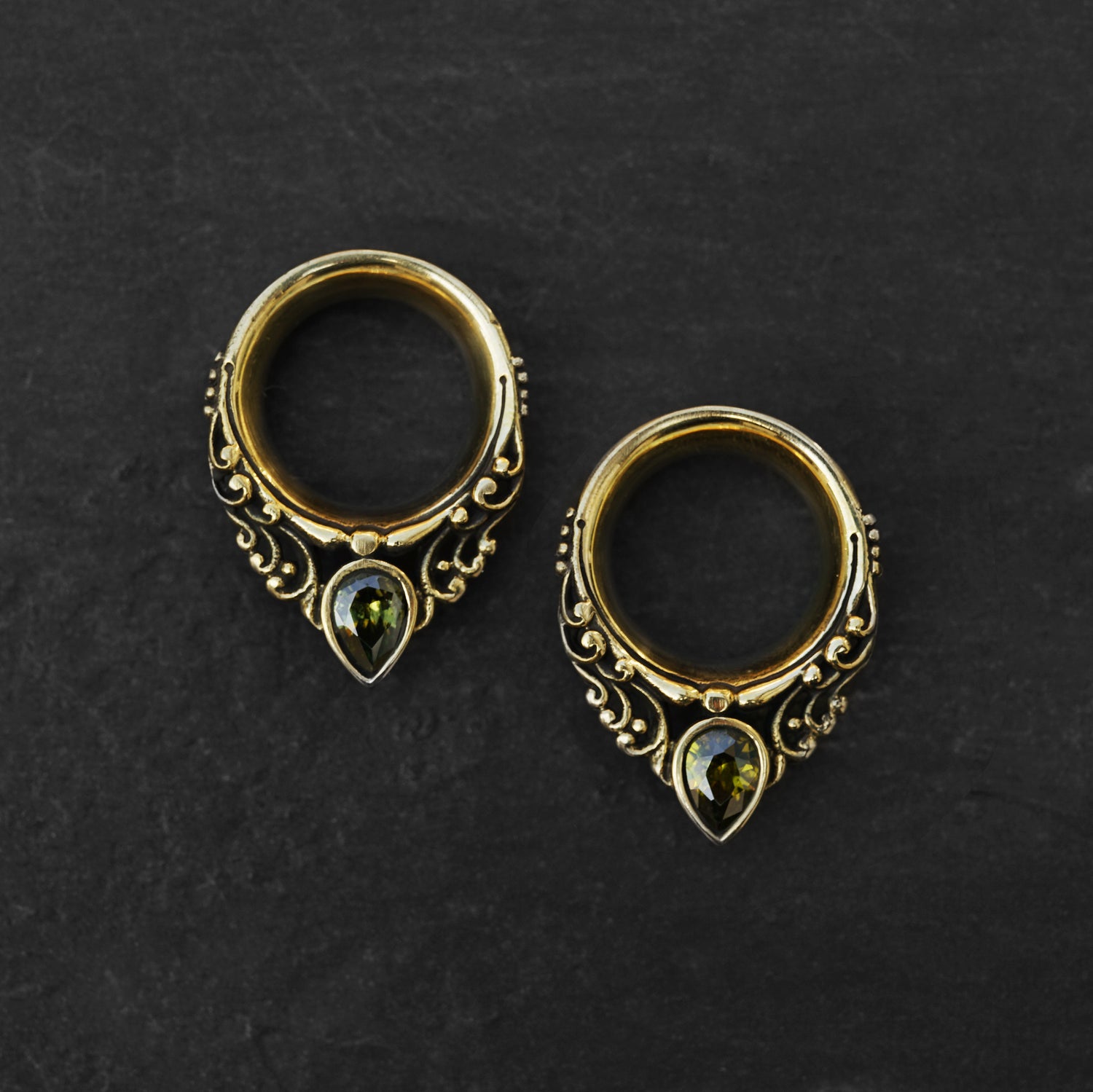 couple of golden victorian ear plugs tunnel in teardrop shape with peridot gem