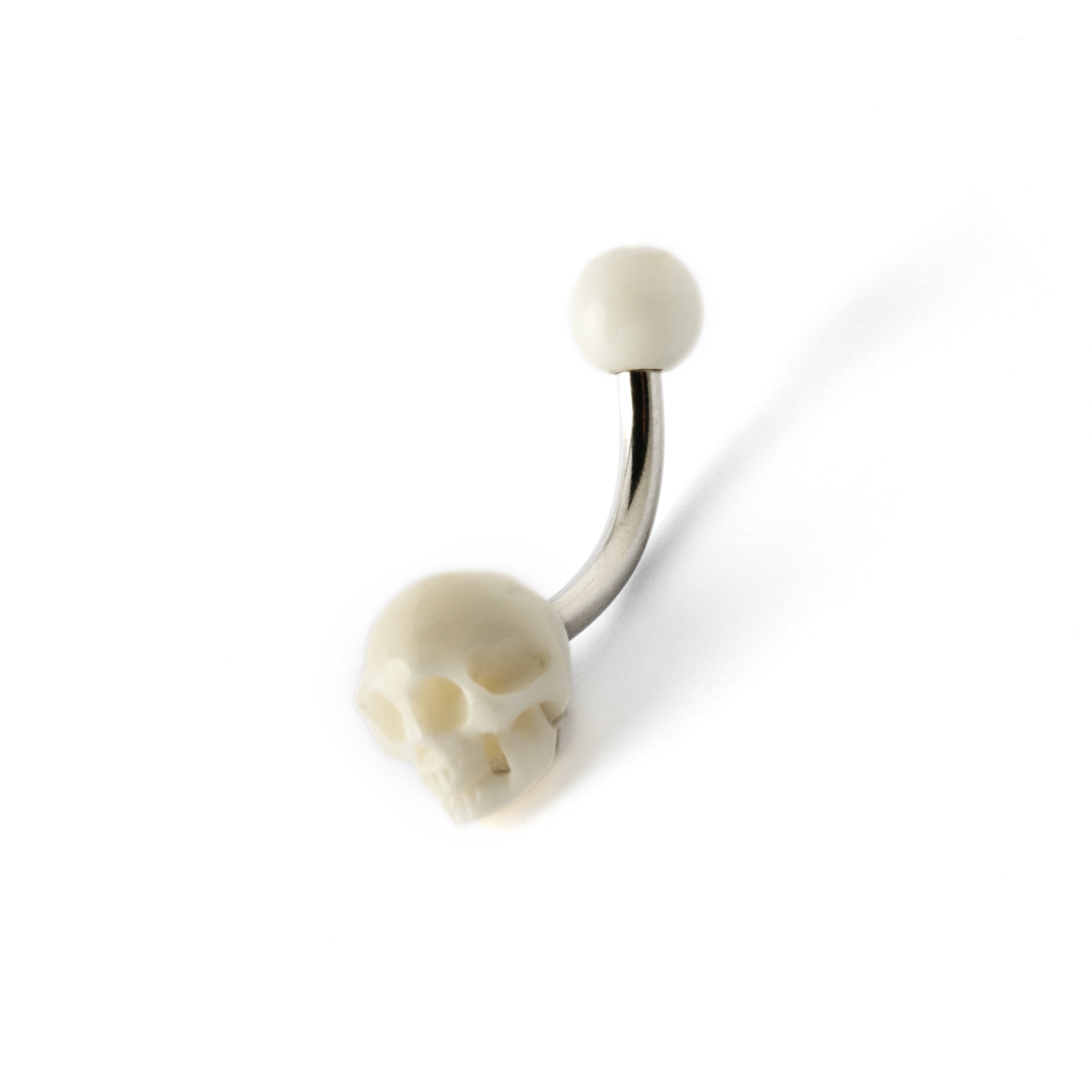 White skull navel piercing on a surgical steel bar left side view