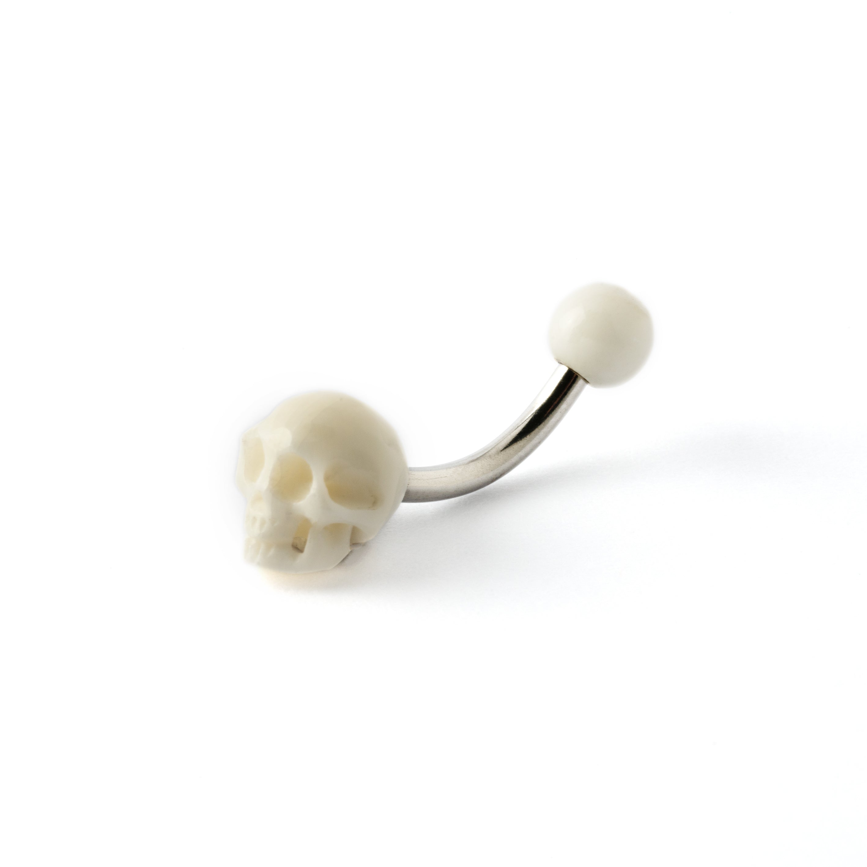 White skull navel piercing on a surgical steel bar