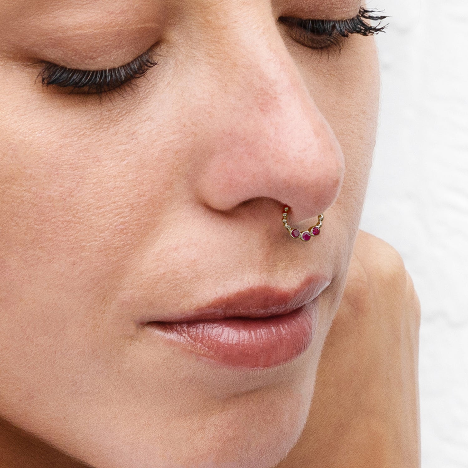 model wearing gold dotted septum ring with three gemstones